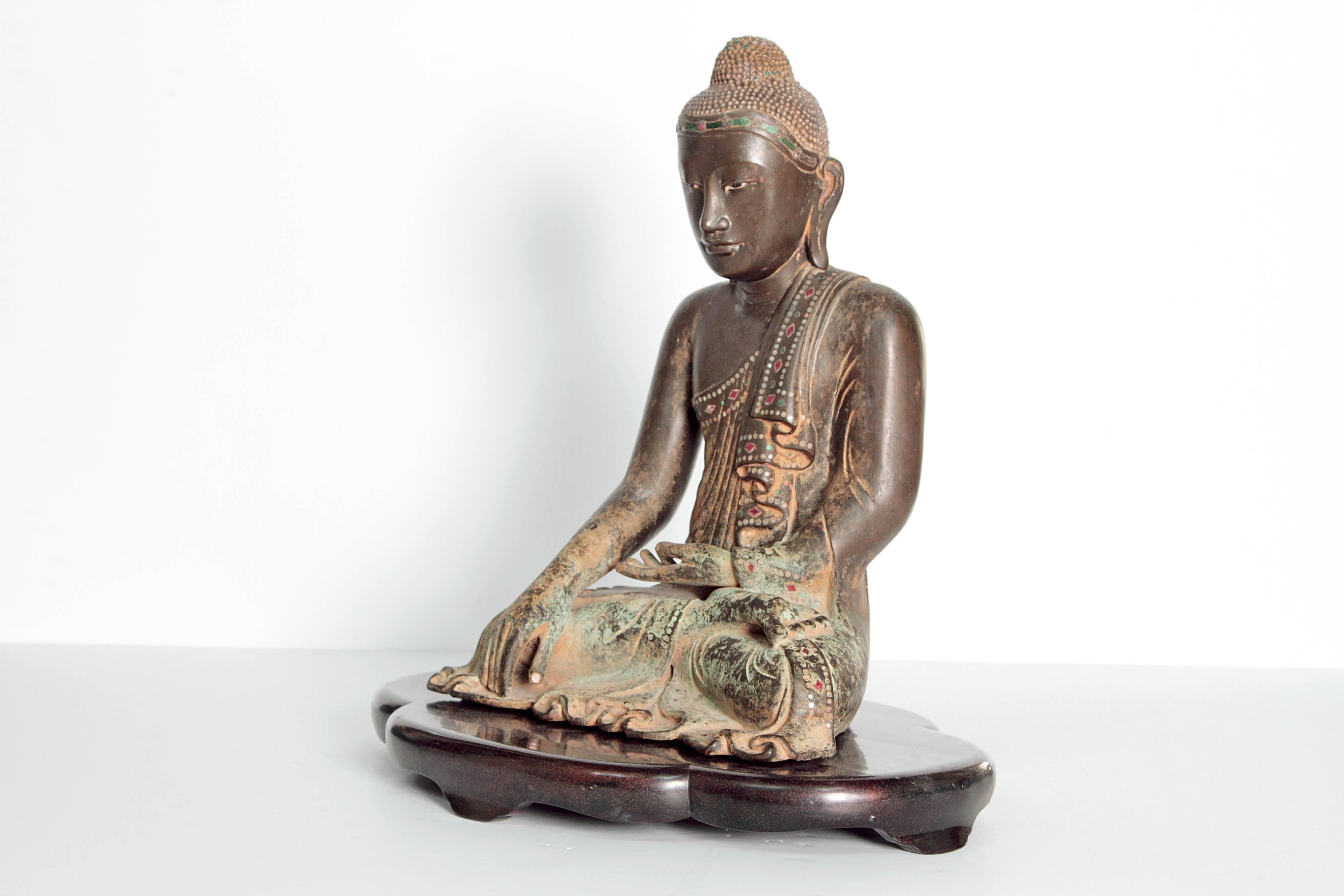 A figure of a 19th century seated Buddha in a meditative pose. Patinated bronze (with Verdigris) accented with colored glass as jewels.