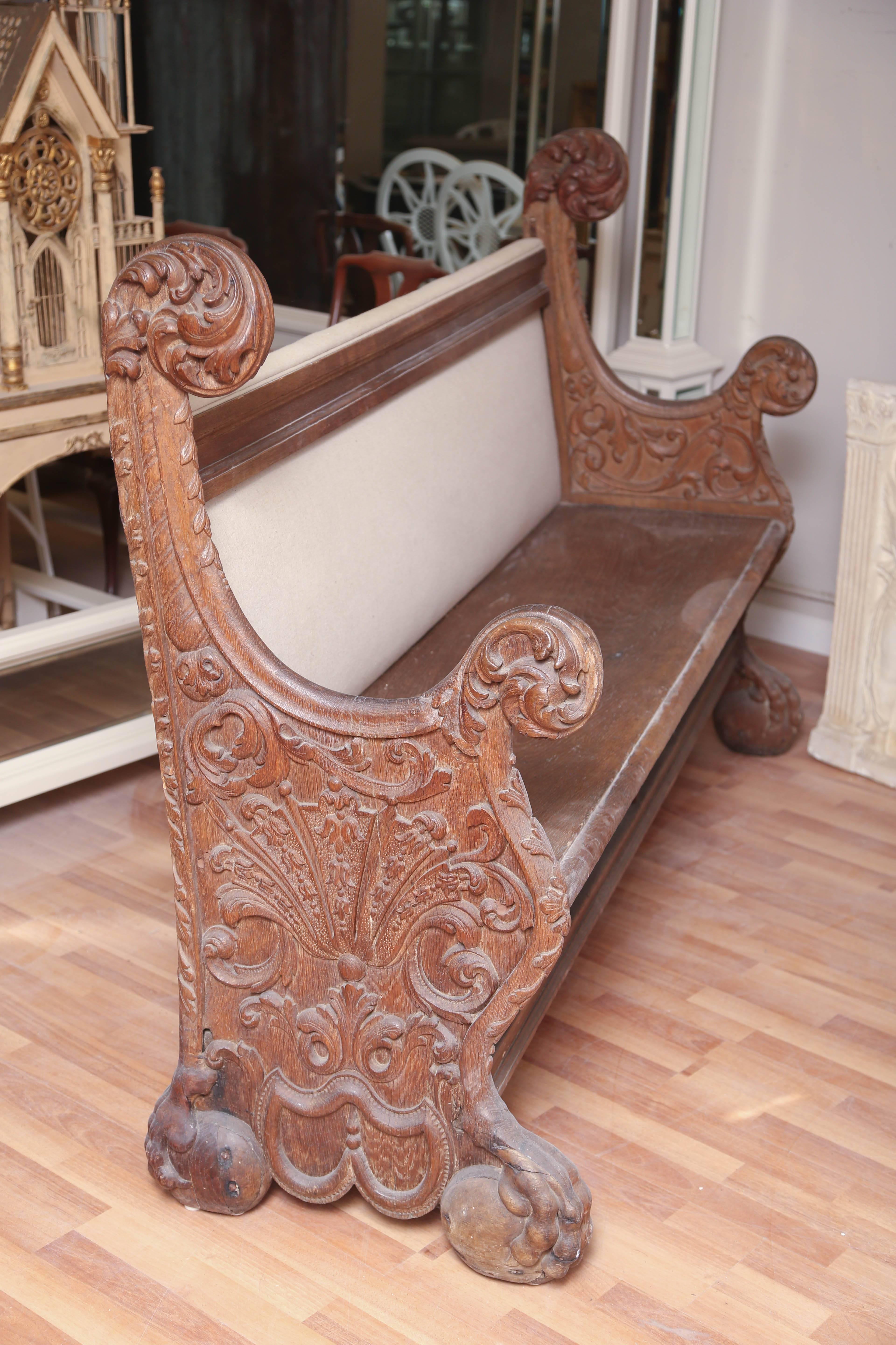 Constructed of oak with great carvings on each end. Back has been upholstered or comfort.