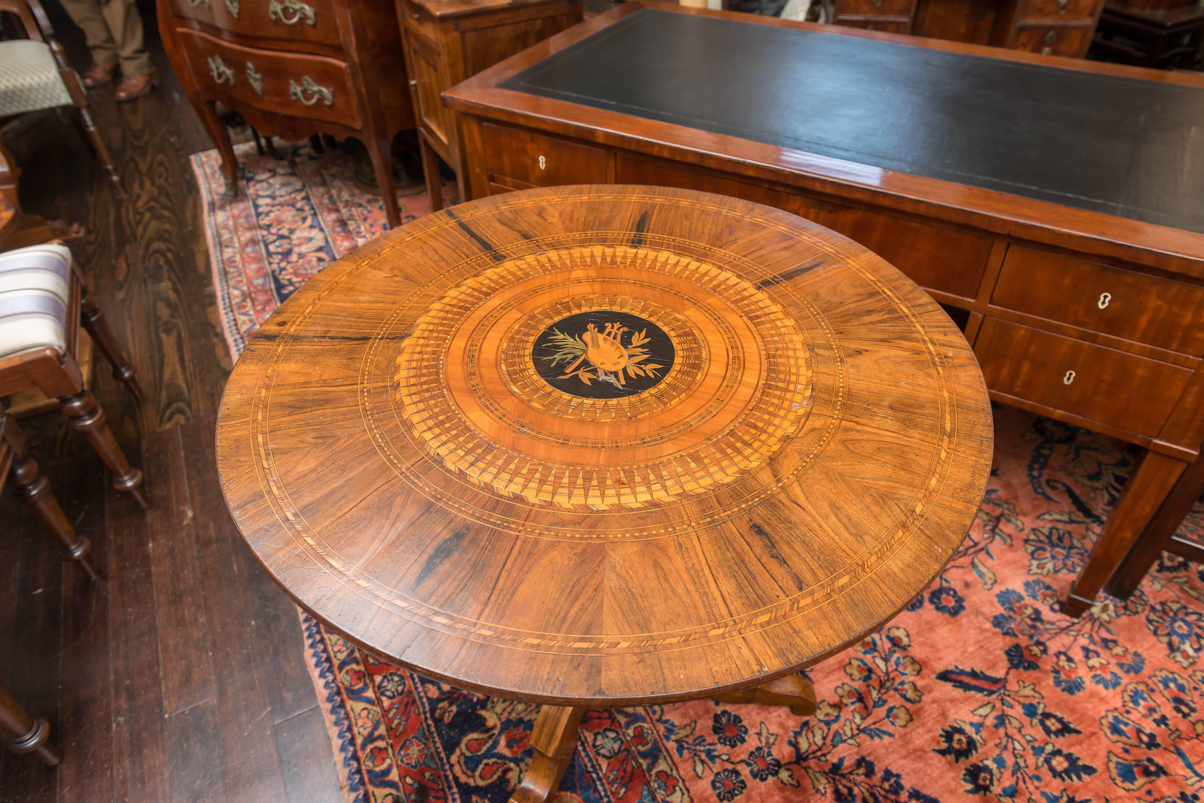 Late 19th Century Southern Italian walnut marquetry center table. Intricate cross banding on the top and the tripod base. The mixture of inlaid woods are walnut and ebony. Stable fixed top and base. Featuring a central trophy of an artist's palette,