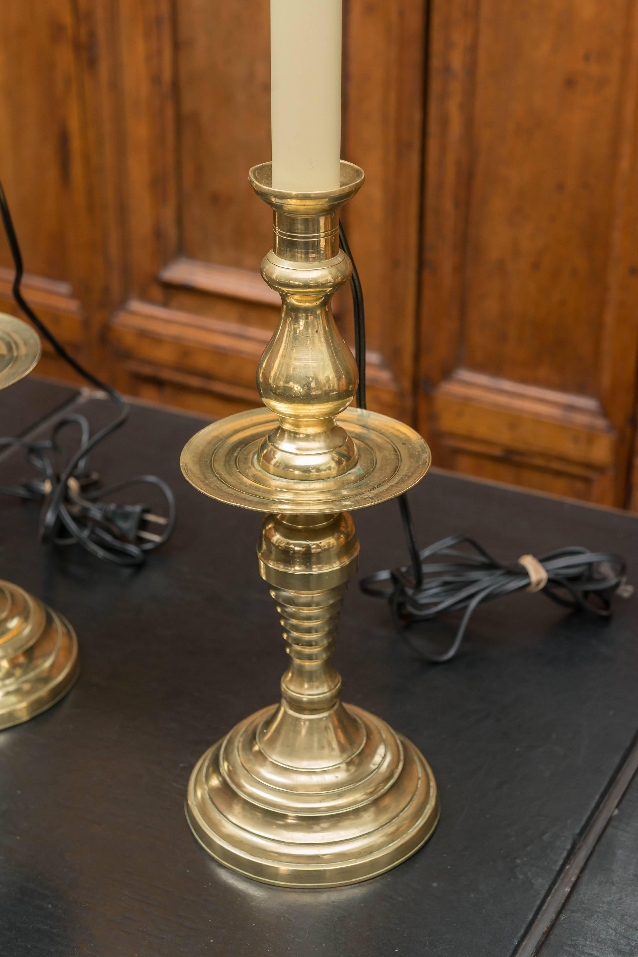Pair Of Late 19th Century Large Scale English Brass Candlestick Lamps. Good old brass color with a high hand polished surface. New  three way sockets and wiring. Fitted with removable harps to accommodate shade size. Candlesticks are 14.5 inches