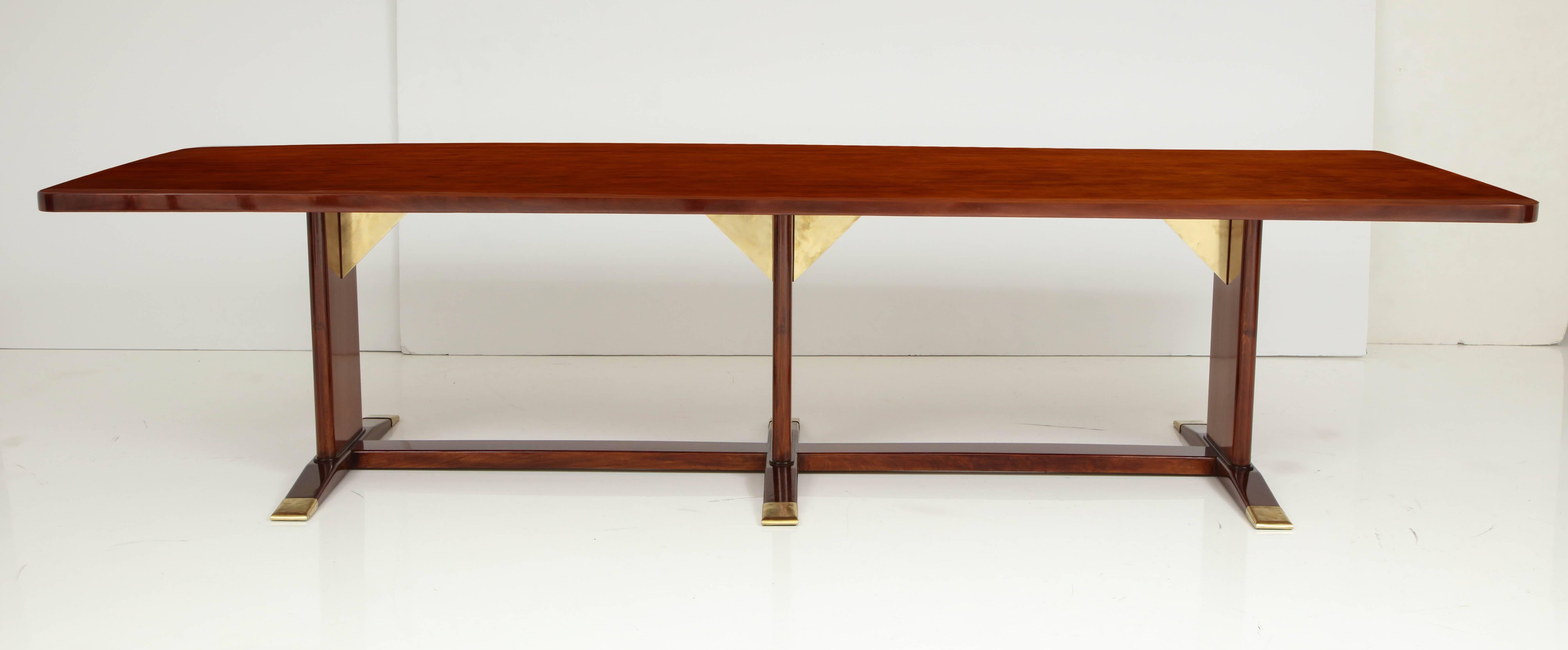 An impressive Frits Henningsen mahogany and brass-mounted table, circa 1940s, the rectangular top with rounded corners raised on three solid supports with brass triangular brackets, with tapered feet ending with conforming brass caps.
Probably a
