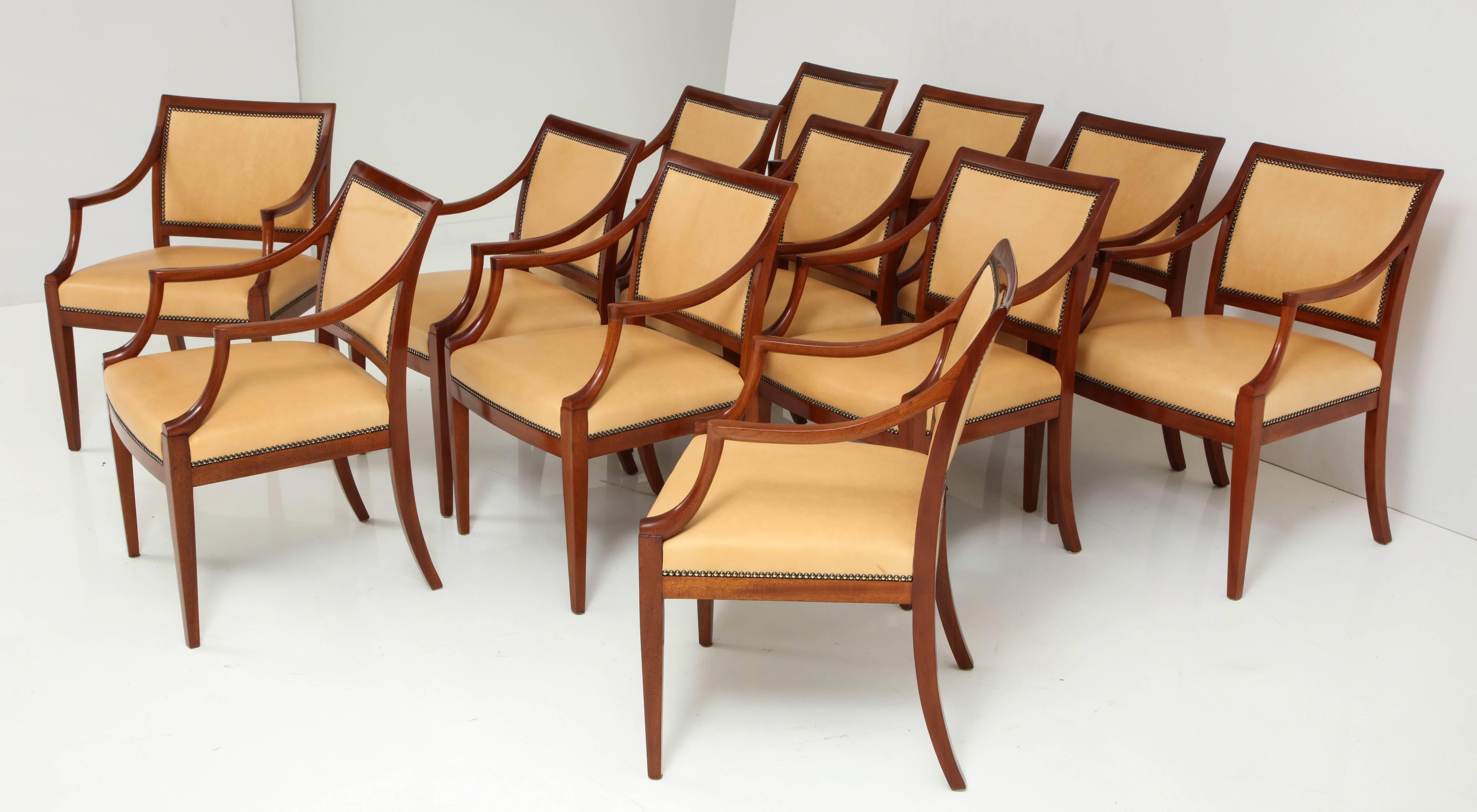 A set of 12 Frits Henningsen mahogany open armchairs with leather seat and back finished with French nailheads, circa 1940s, a rich mahogany frame with downswept armrests raised on square tapered legs. New leather upholstery. 

Price is per