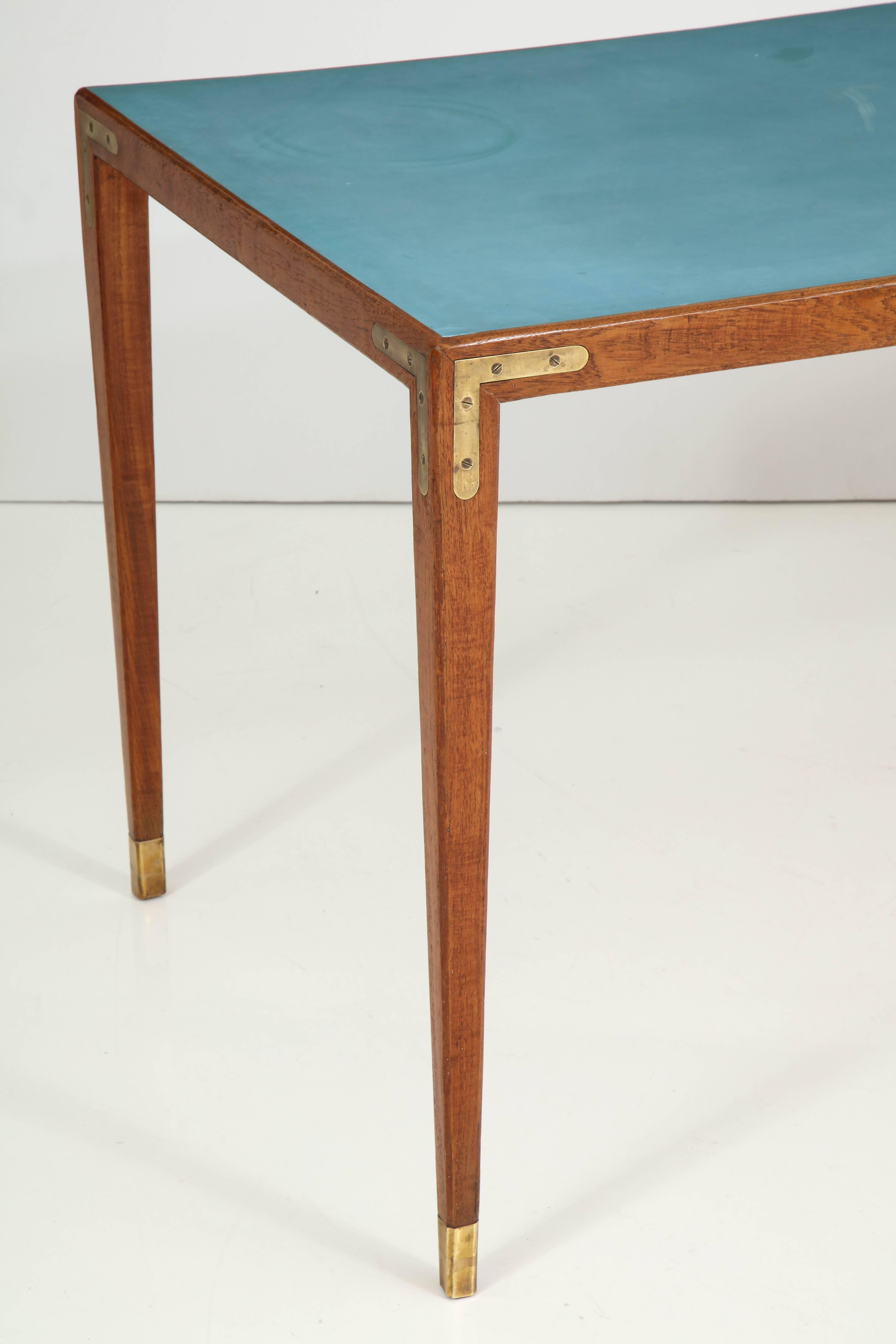 A Danish architect designed table, circa 1960s, the rectangular blue Formica inset top with an oak frieze, the square tapered legs headed with inset right angle brass brackets and ending with brass caps.

 