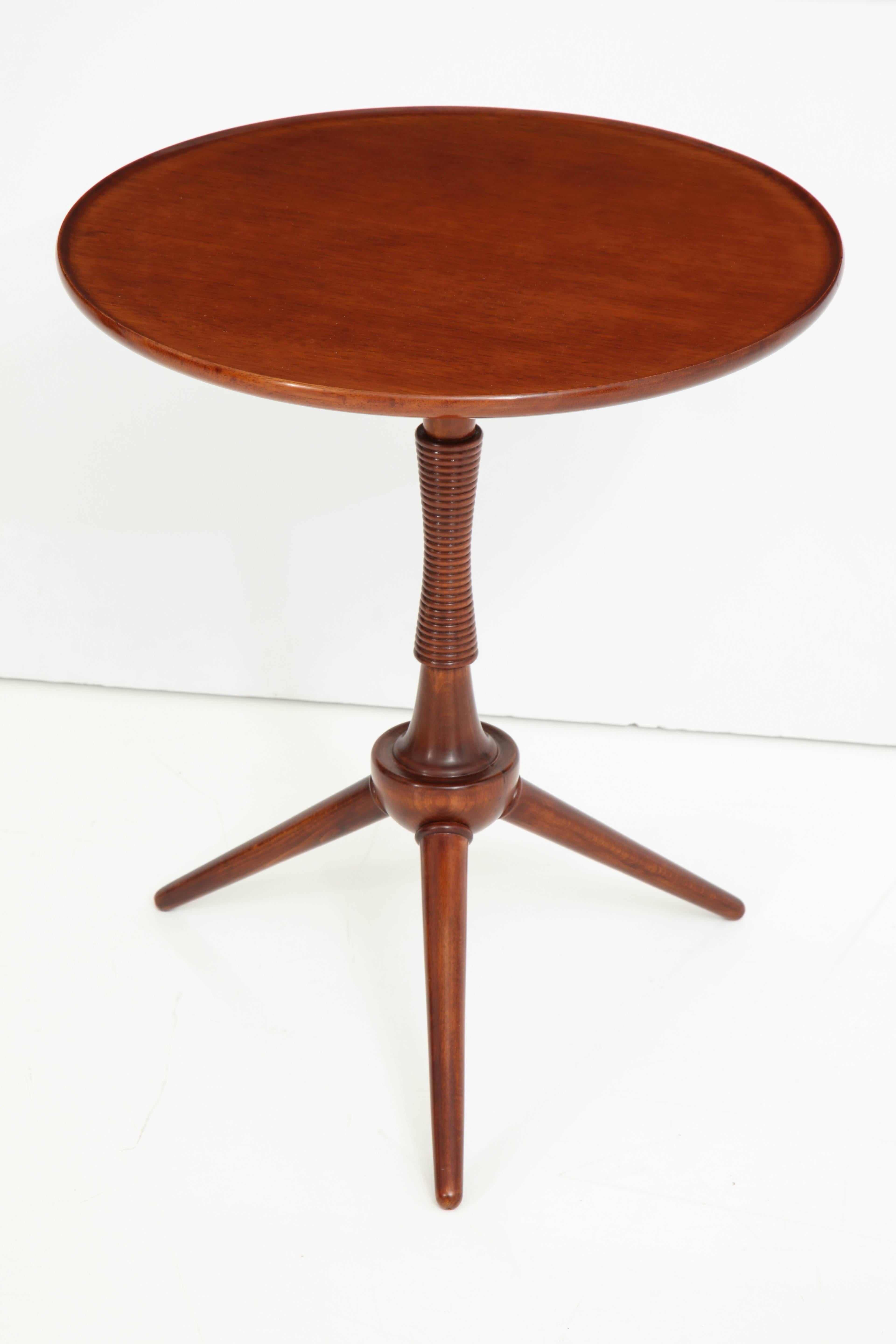 A Danish mahogany tripod table, circa 1940s, designed and produced by Frits Henningsen, with a circular lipped top raised on a partially spool turned tapered and spreading stem ending with three circular tapered legs.
   