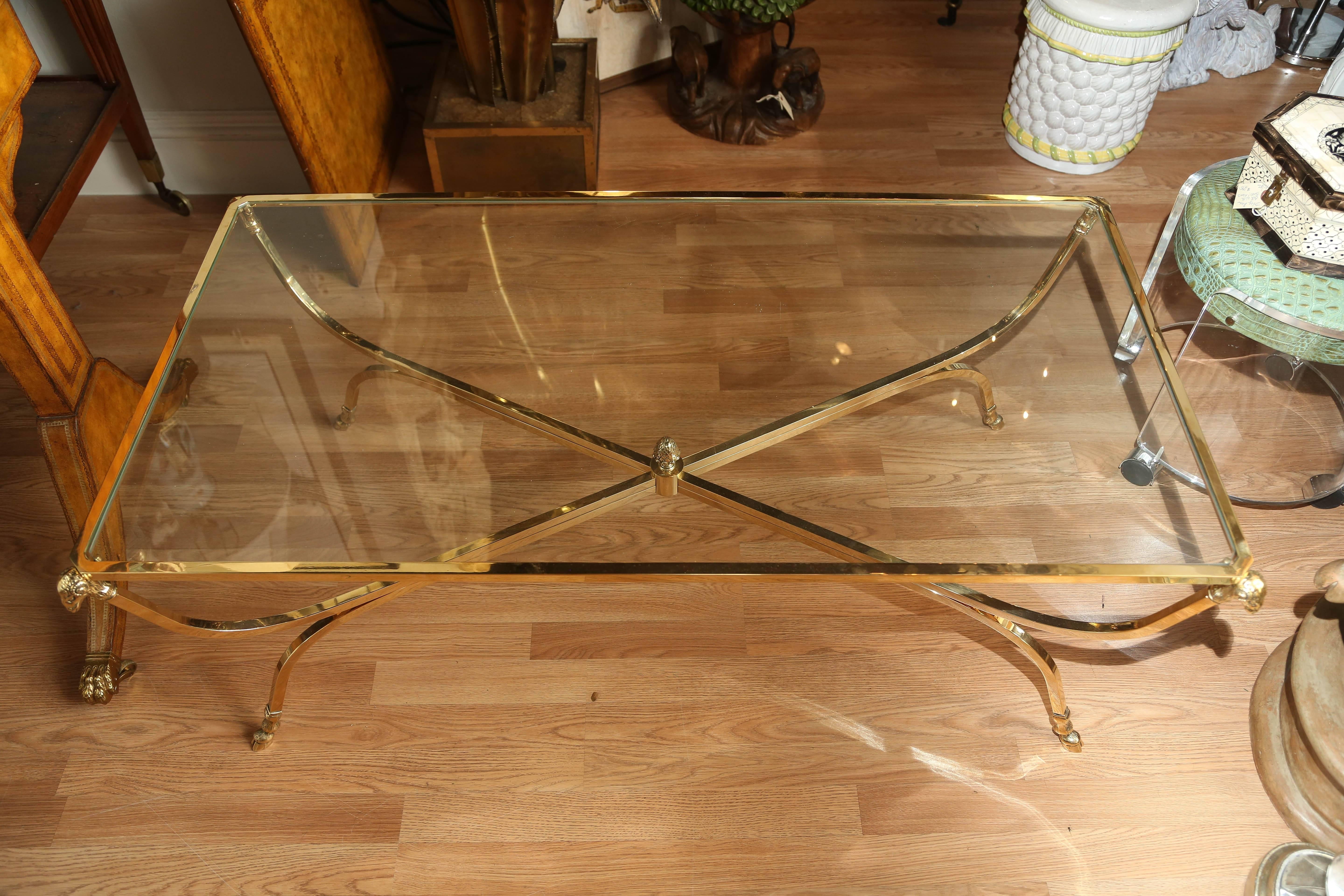 Solid brass rectangular coffee table with ram's heads on all corners and hoofed feet.