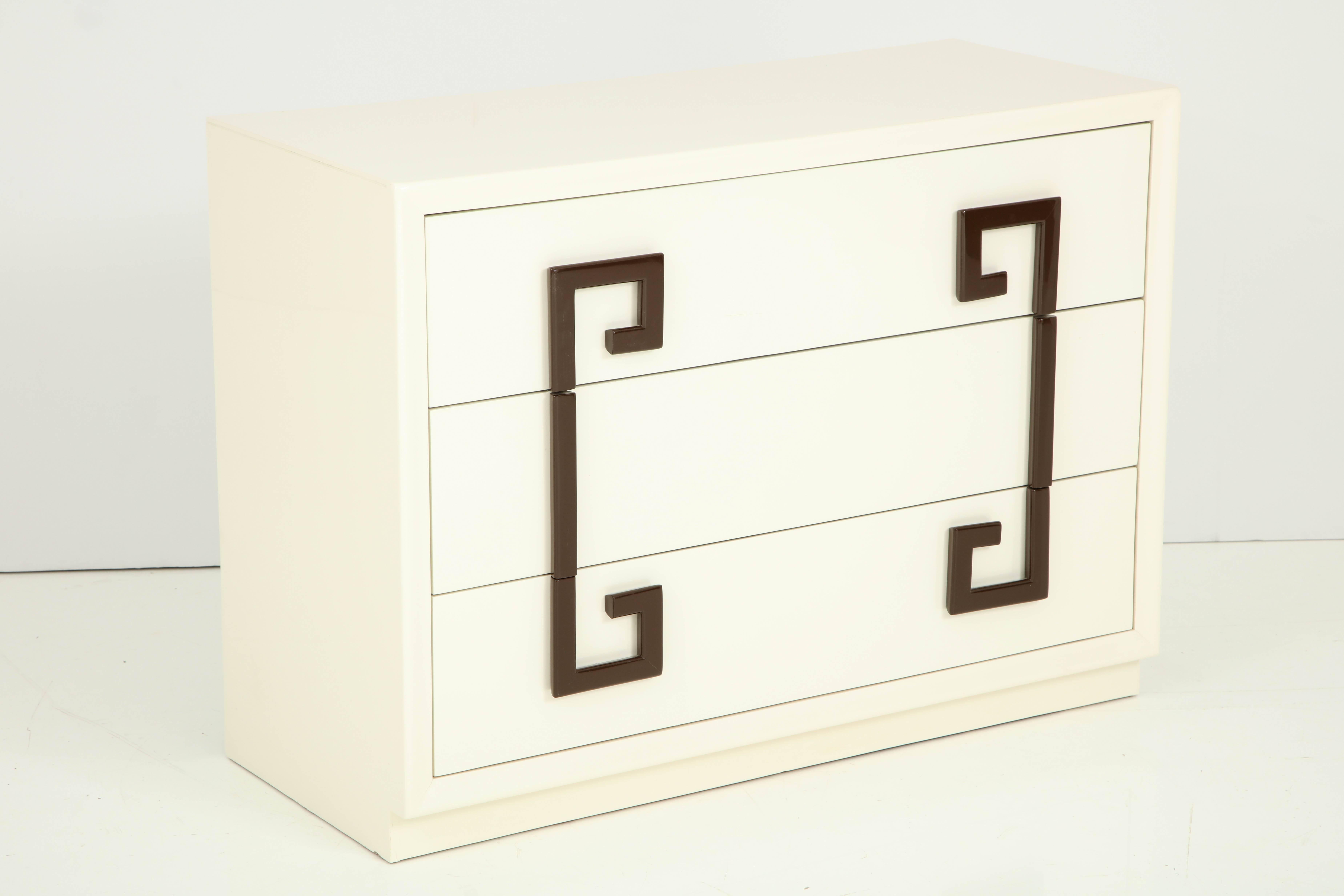 Hollywood Regency chest of drawers in a sophisticated Ivory lacquer with contrasting stylized Greek key pulls in a chocolate brown lacquer, Kittinger c40's. Mint Restored.