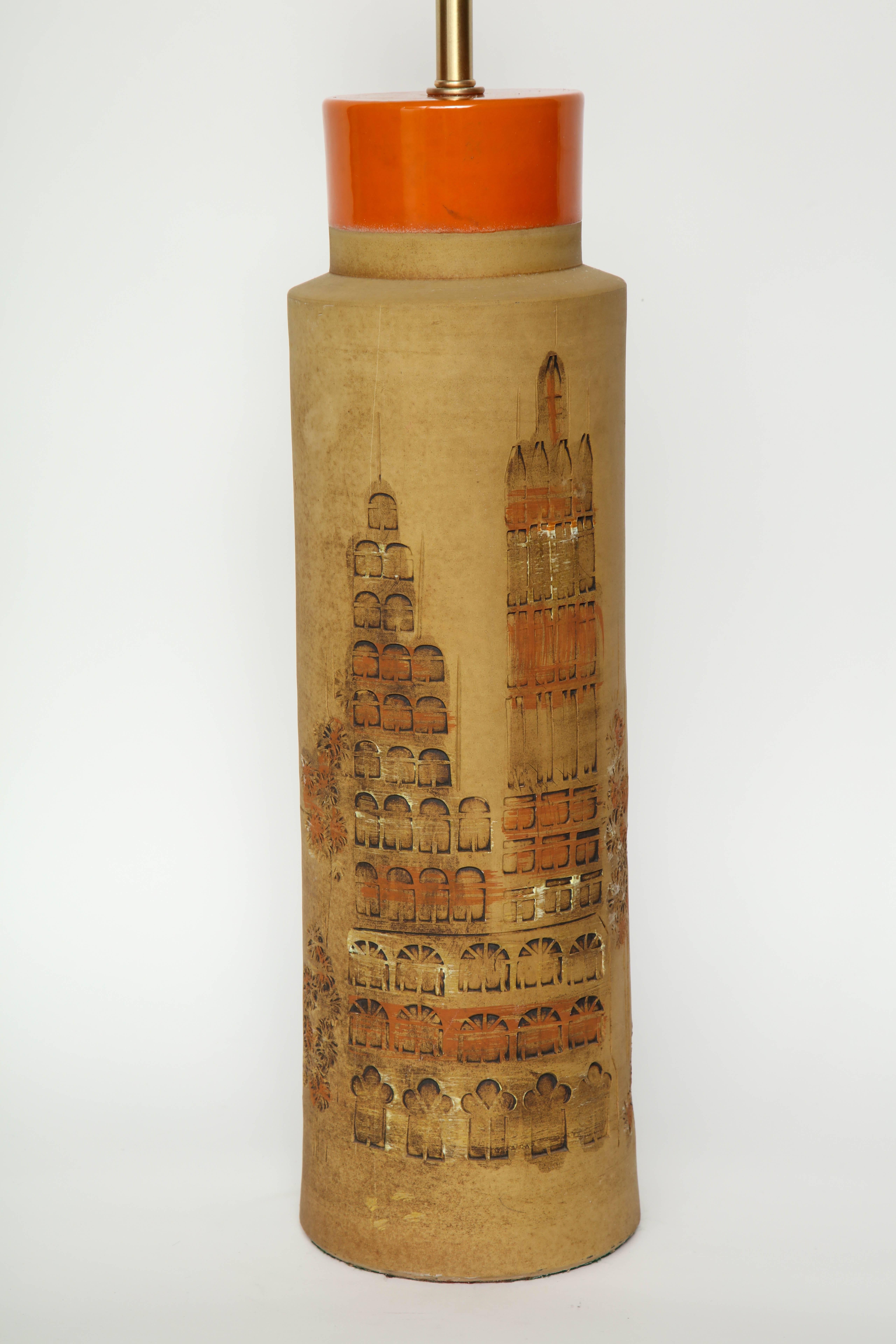 Paire de lampes cylindriques italiennes classiques du milieu du siècle dernier, avec des détails appliqués à la main en stampato représentant des bâtiments constituant la ligne d'horizon d'une ville, le tout couronné d'un vernis orange. Recâblé pour