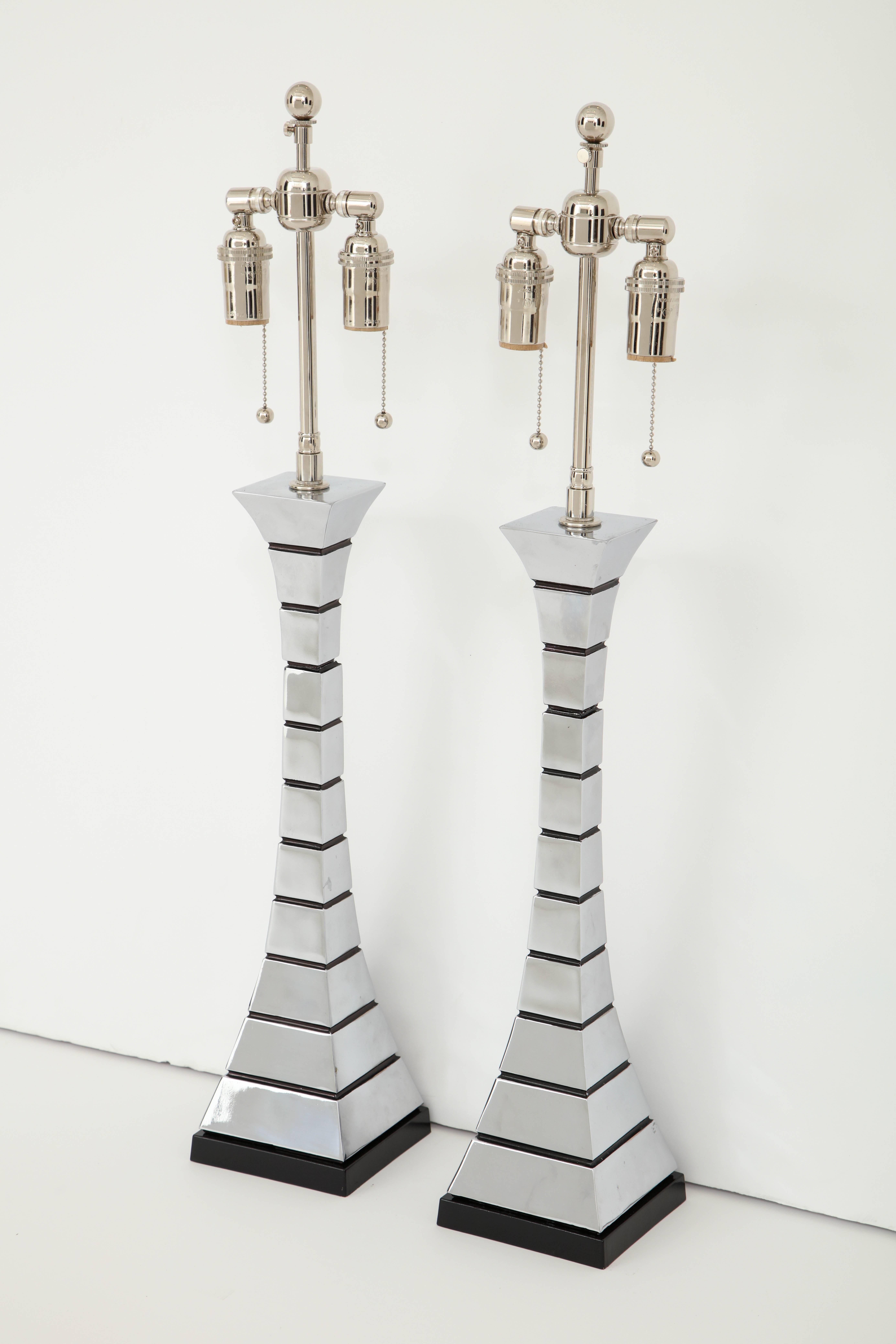 Pair of 1970s midcentury polished chrome lamps.
The lamps have a wonderful Eiffel Tower feel to them with a subtle hour glass shape which is alternated by painted black horizontal channels.
The lamps have been newly rewired for the US with