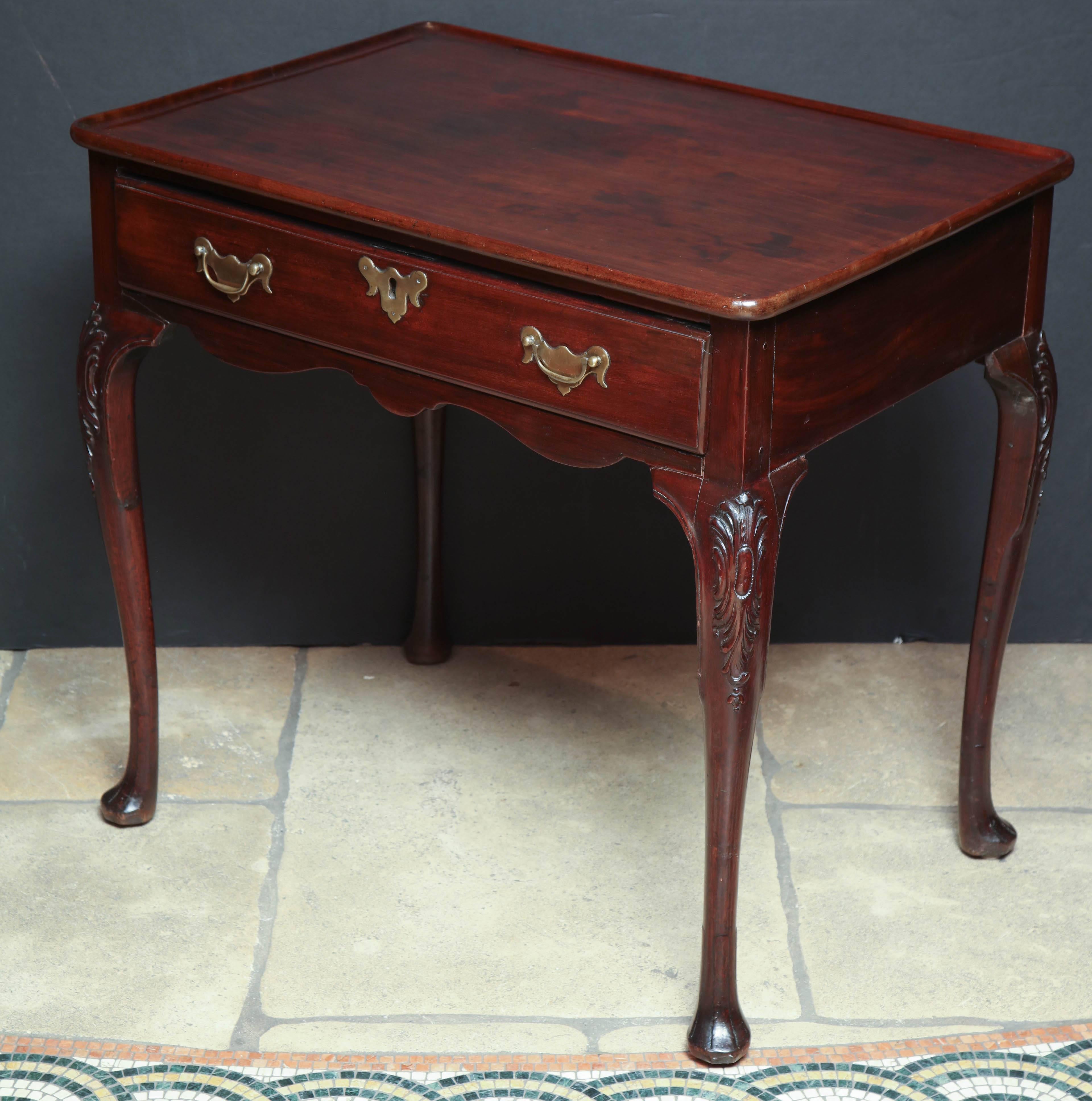 A rare Irish Queen Anne mahogany tray top tea table with long drawer, original hardware, peanut and leaf carved knees on trifid feet.