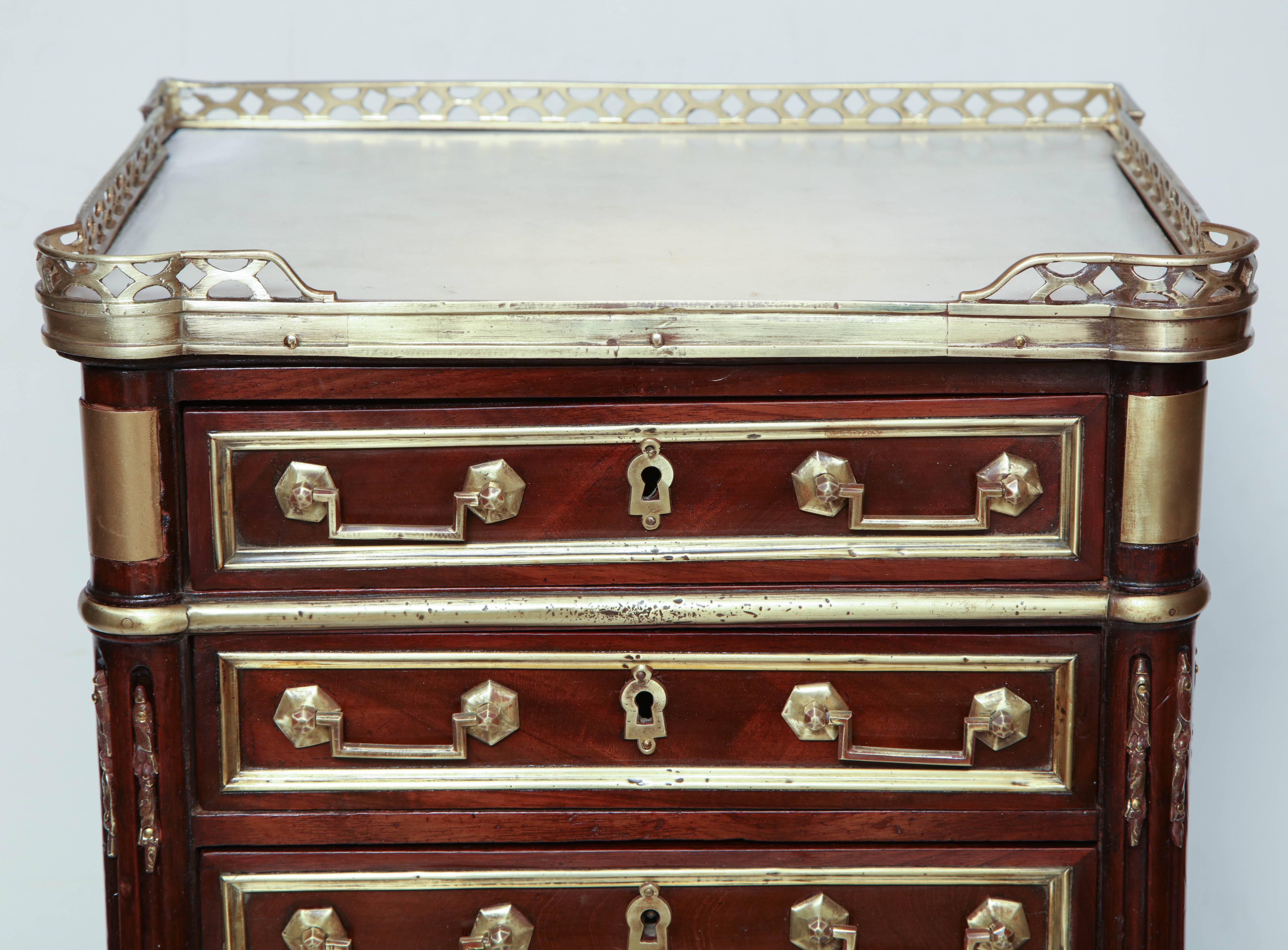 A Louis XVI miniature acajou semanier with marble top, pierced bronze gallery, brass mounts, stop fluted styles on turned taupe feet.