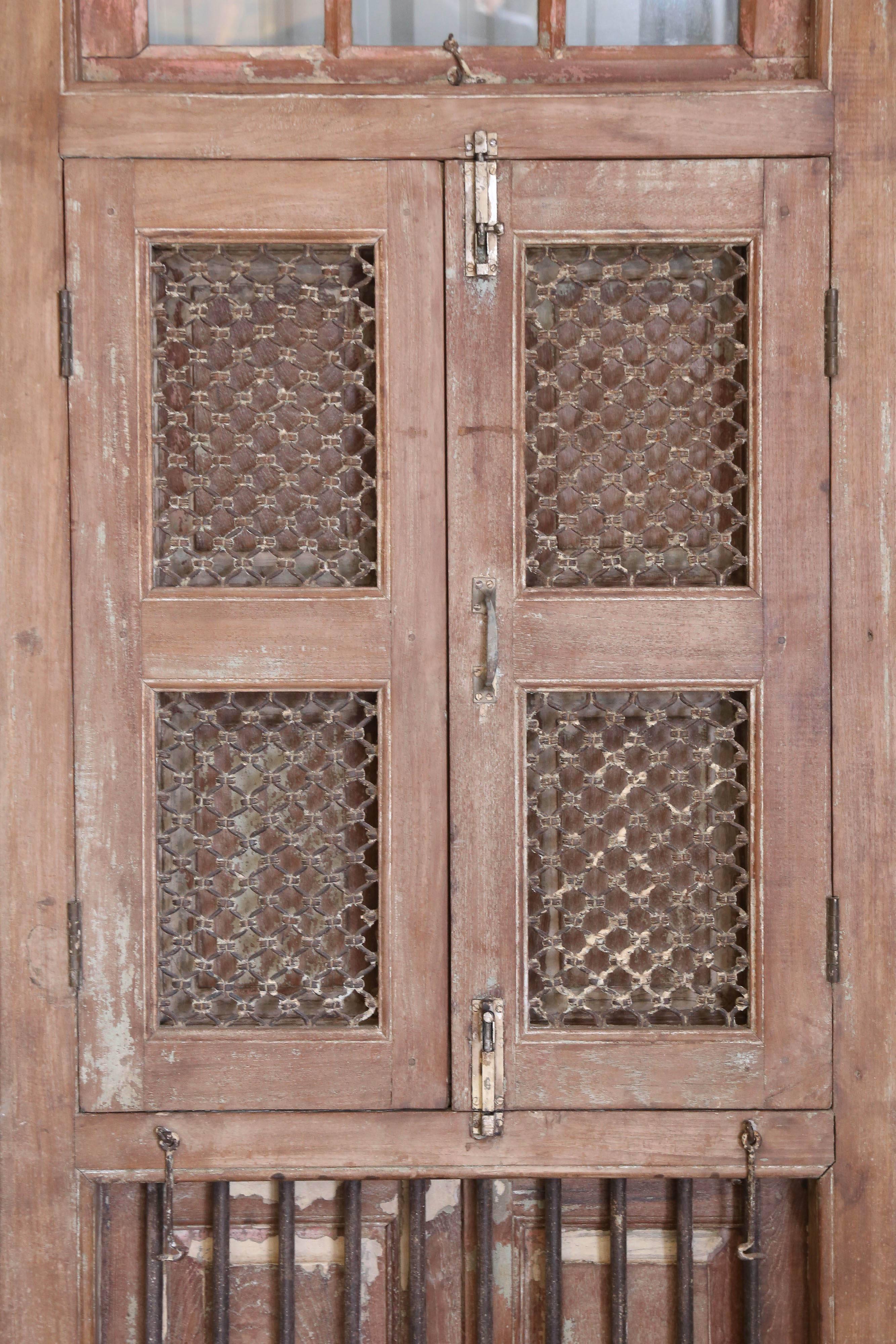 This elaborate solid teak wood window with intricately hand forged iron works comes from a Portuguese colonial church built in west coast of India in the early 19th century. It is made of solid teak wood with hand forged iron bars and iron screen.