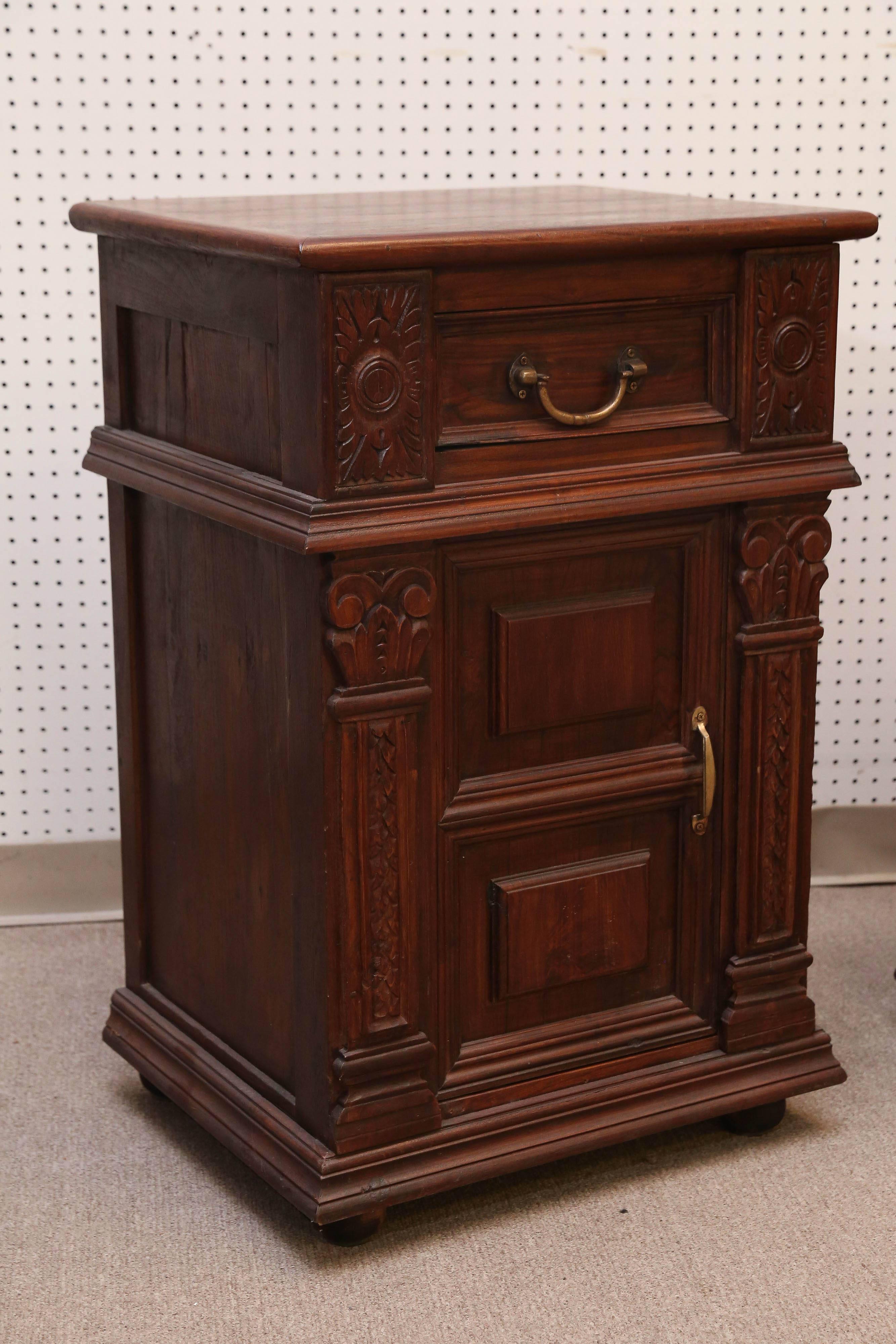 Early 20th century solid teak wood night stands from a British Colonial home. These are nicely carved with pillar design in front and ball feet. It has an upper drawer and a bottom shelf. Heavily made to last several generations.
Such high quality