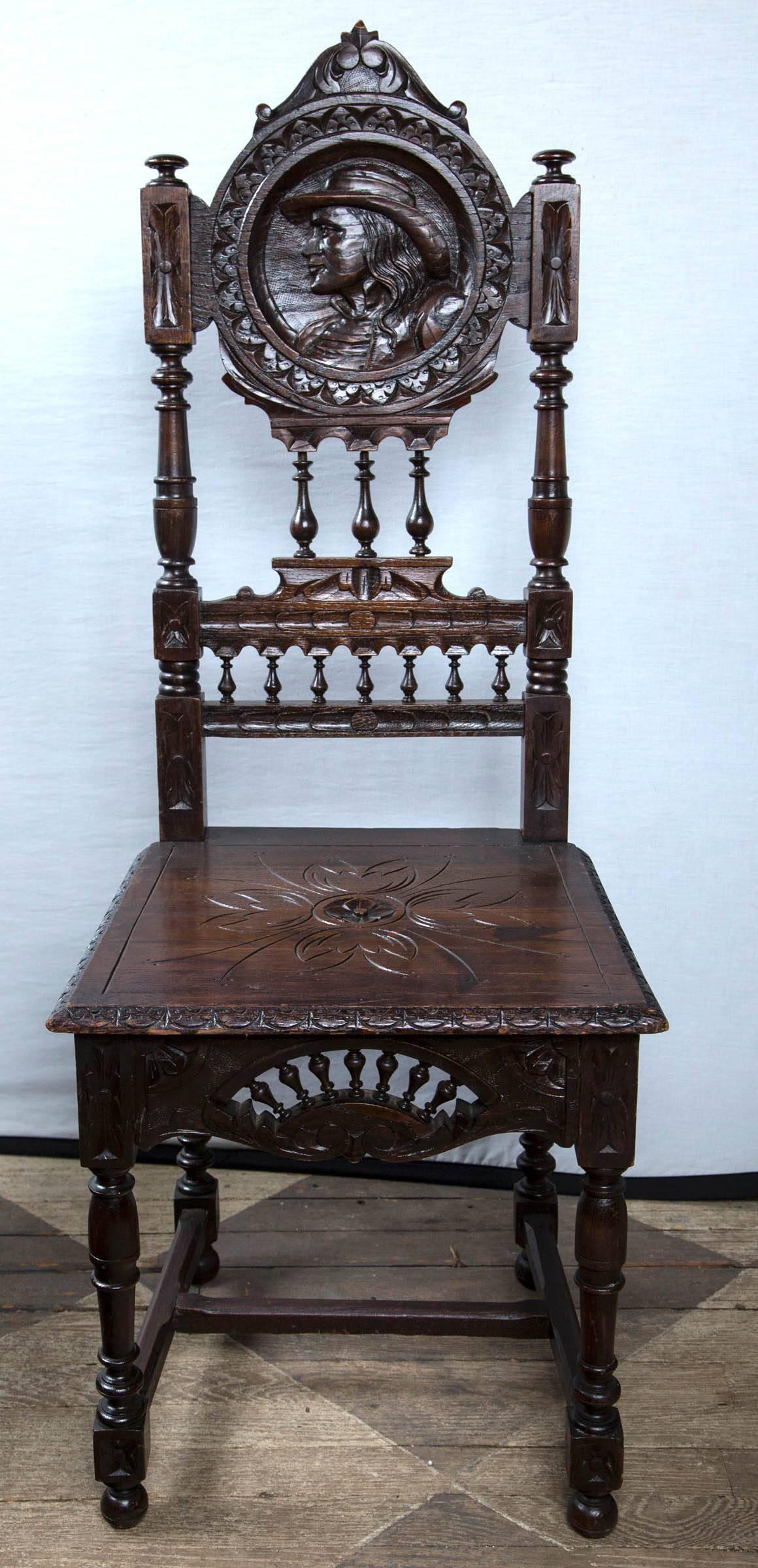 Each with a carved profile head on the back. One of a woman and one of a man. Carved floral on seat. Spindles on back, and front apron.