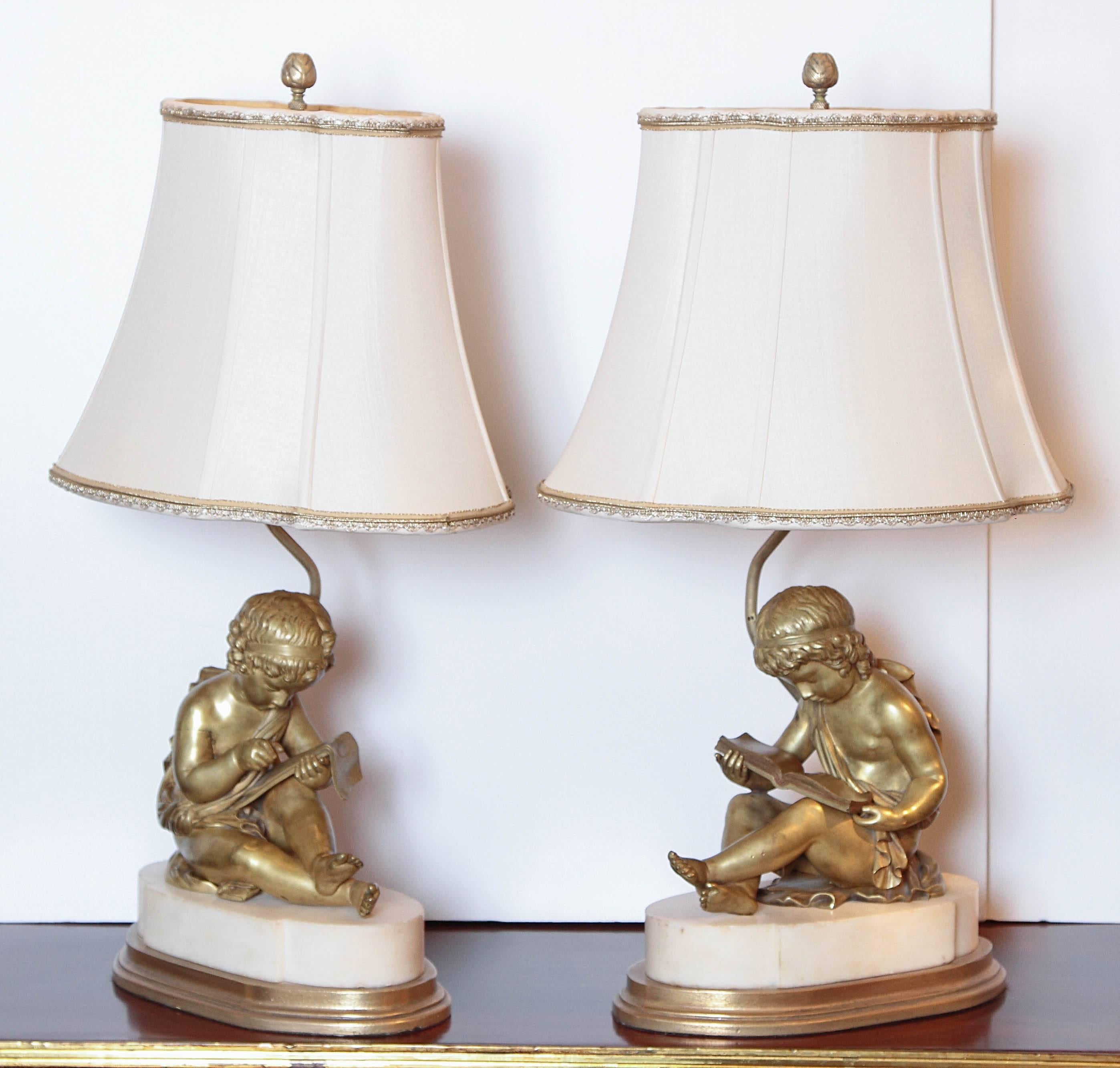 Pair of finely cast 19th century French gilt bronze children reading on white marble bases. Made into lamps custom wired and shaded.
