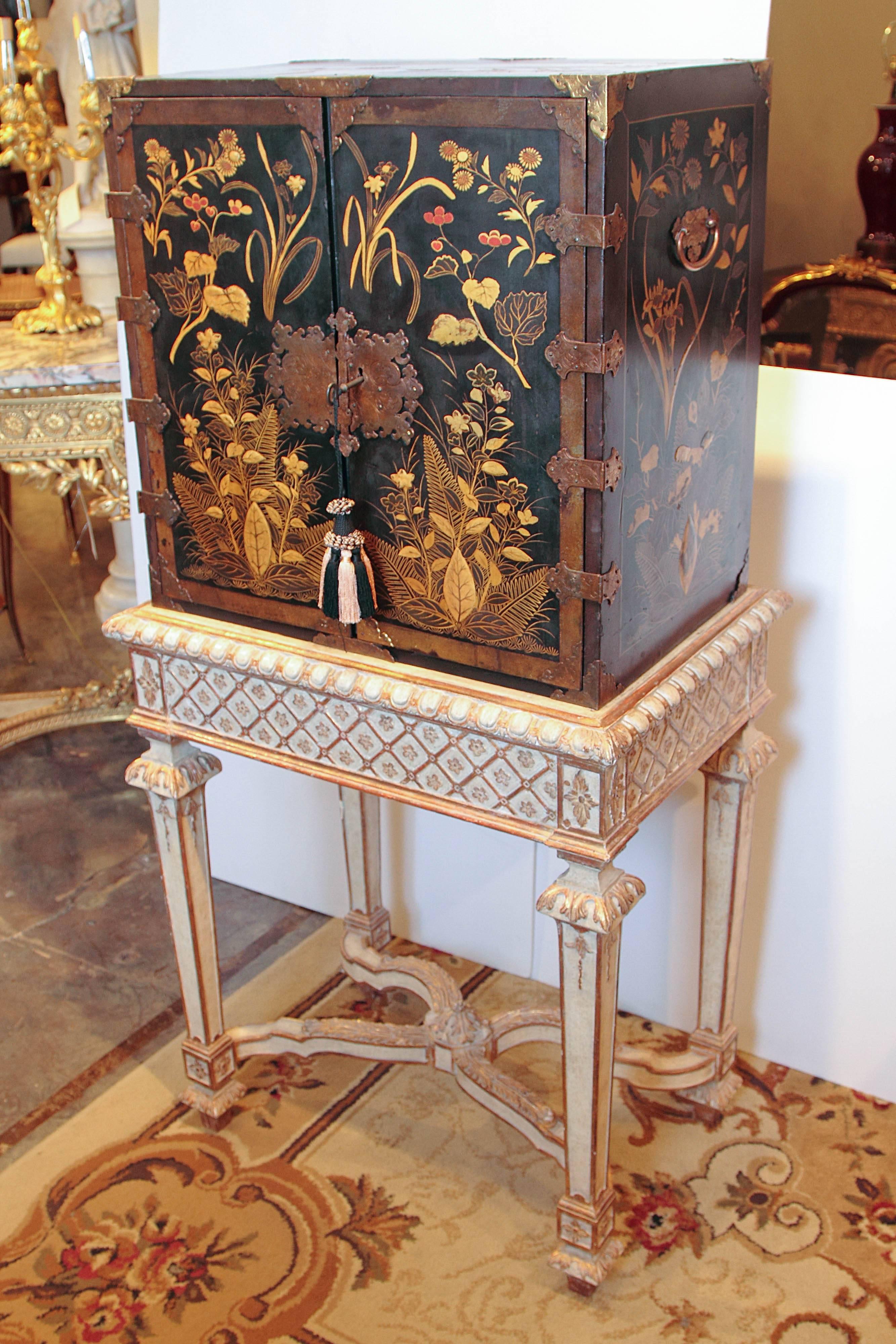 A rare and fine pair of 19th century English black lacquered and Japanned cabinets with raised leaves, plants and vine design in the Asian taste. The cabinets open to reveal illuminated glass shelving and three drawers. One interior drawer with