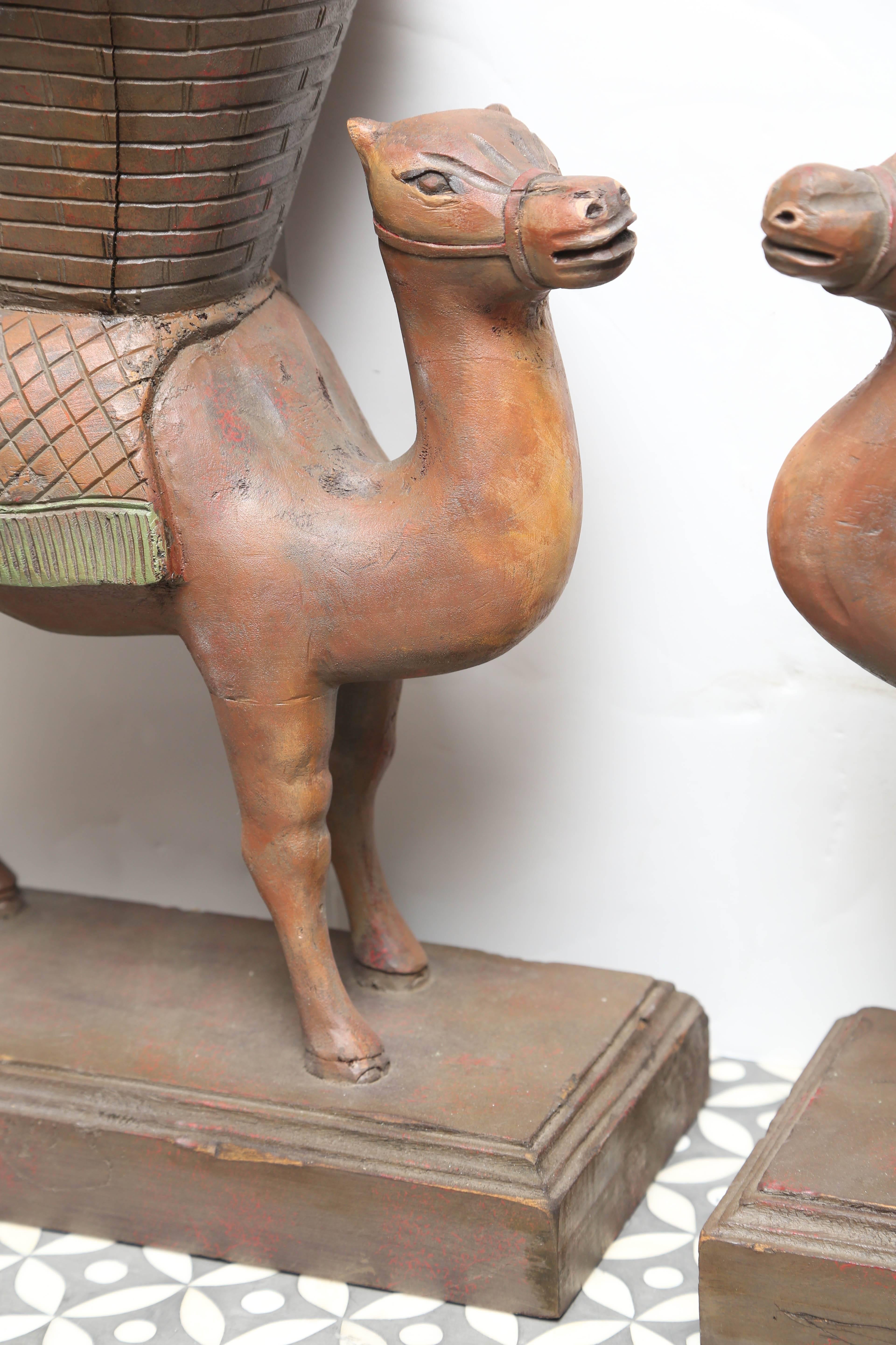 A neatly carved opposing pair of camels with subtly painted finishes and generous scale.