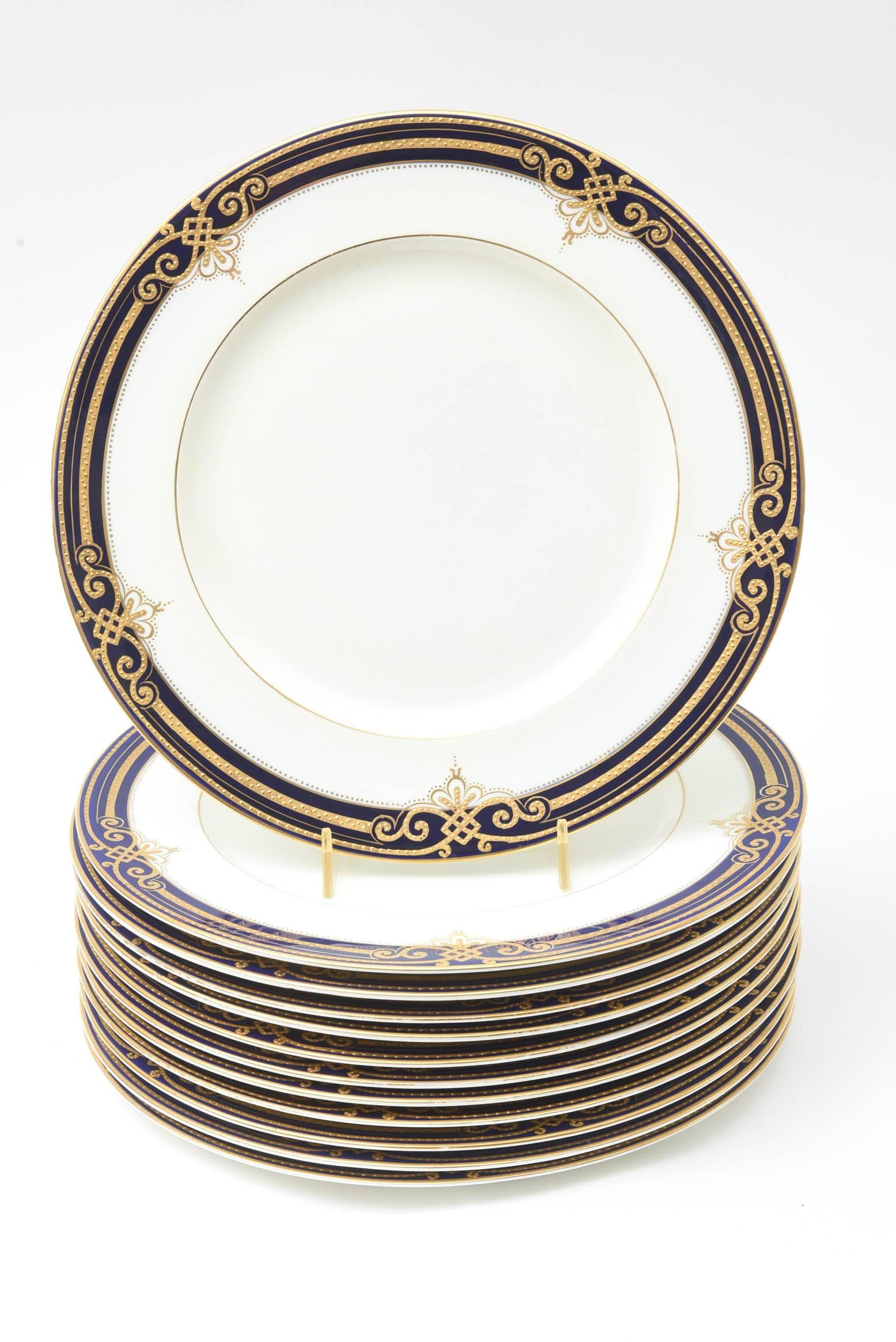 12 fine porcelain dinner plates from George Jones, England and custom ordered through the fine retailers of Ryrie Brothers, Toronto. Crisp white ground with an intricate design on its collar with very detailed raised tooled gilding along with the