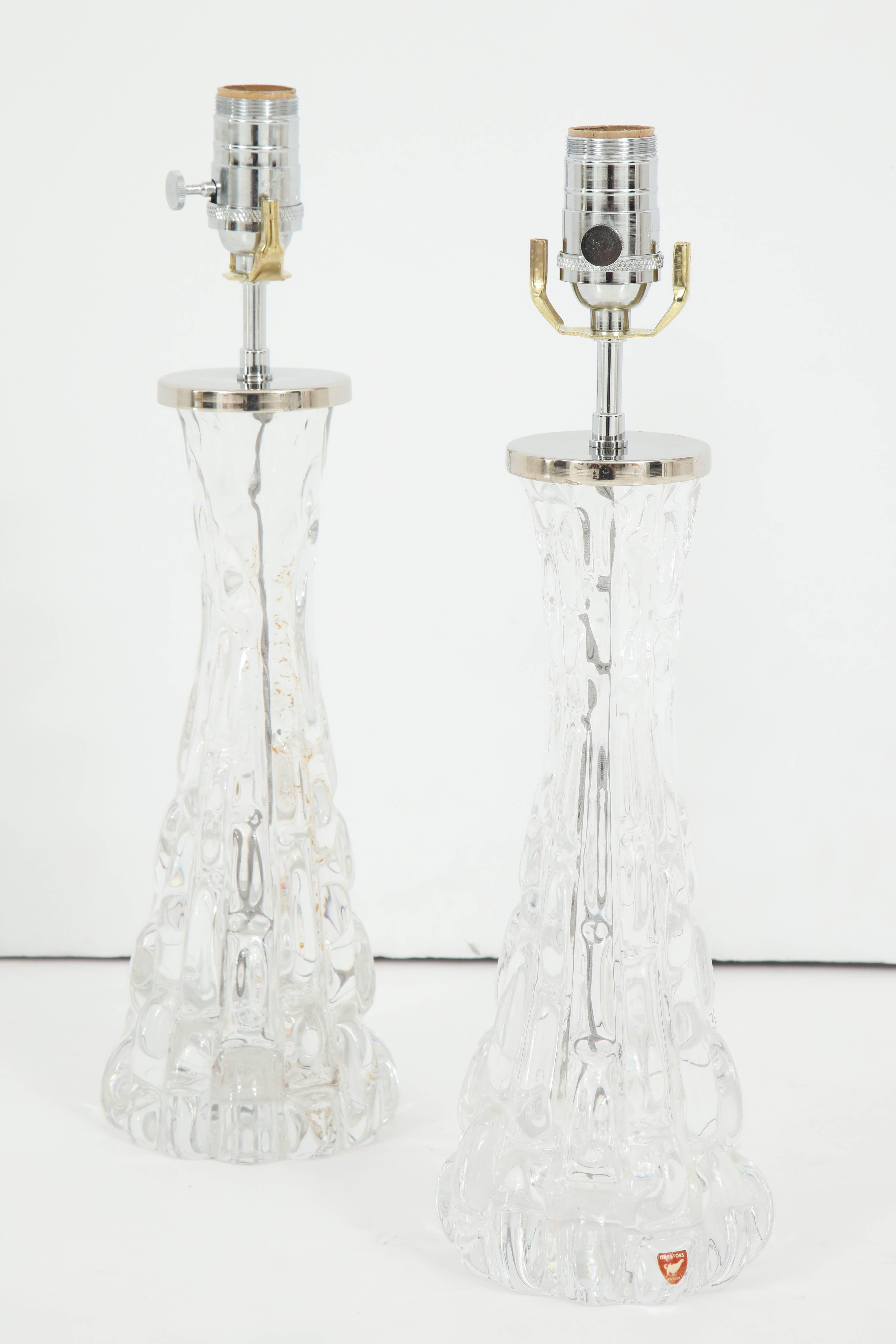 These stunning clear lamps have a sculptural quality about them. Created by Orrefors Crystal, the lamps have an hourglass form, with a textured appearance, almost like ice. They have been recently re-wired for use in the US, and have fabric cords.