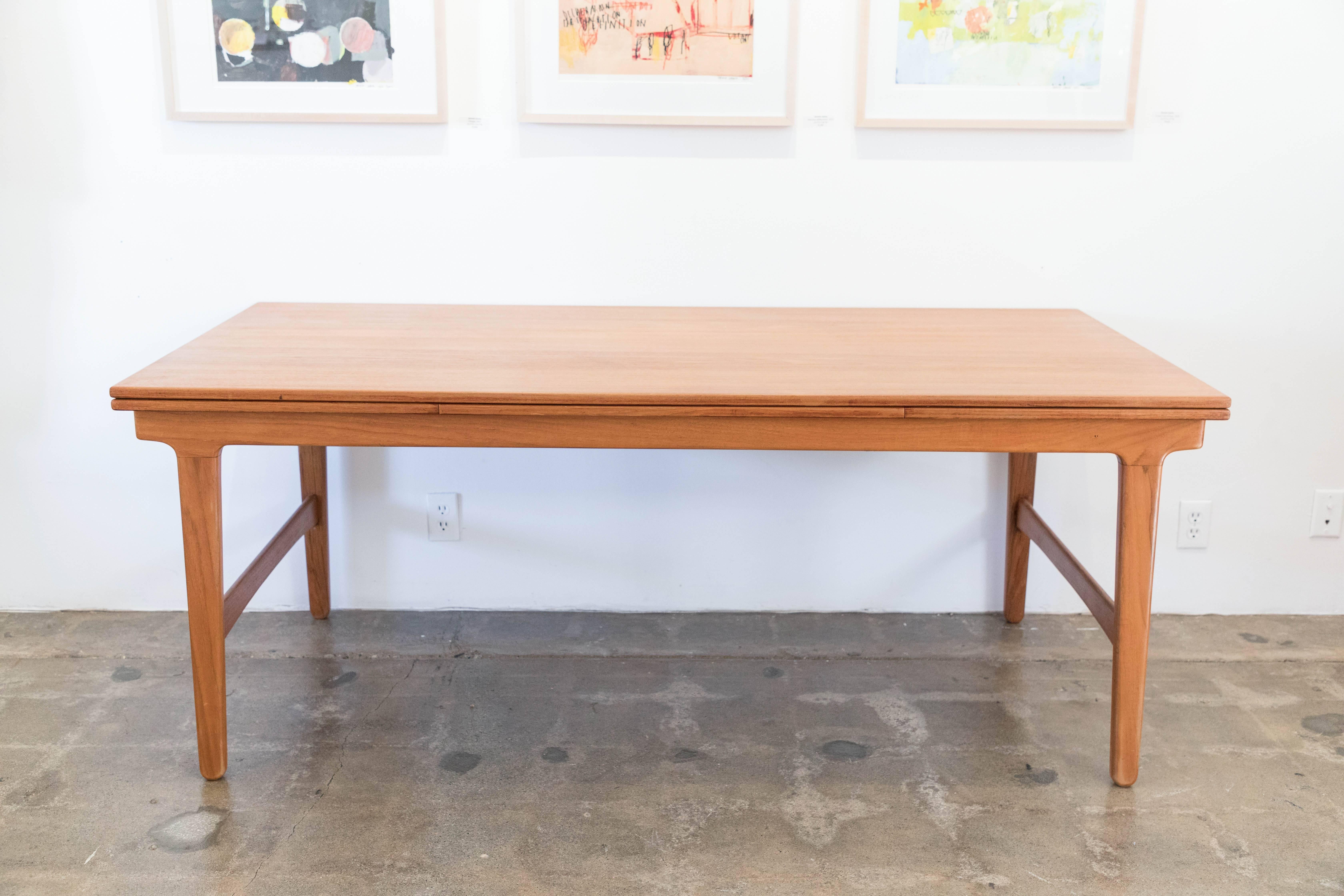Danish modern expandable dining table with leaves concealed in the body of the table underneath.
Length of table fully extended with leaves is 113
