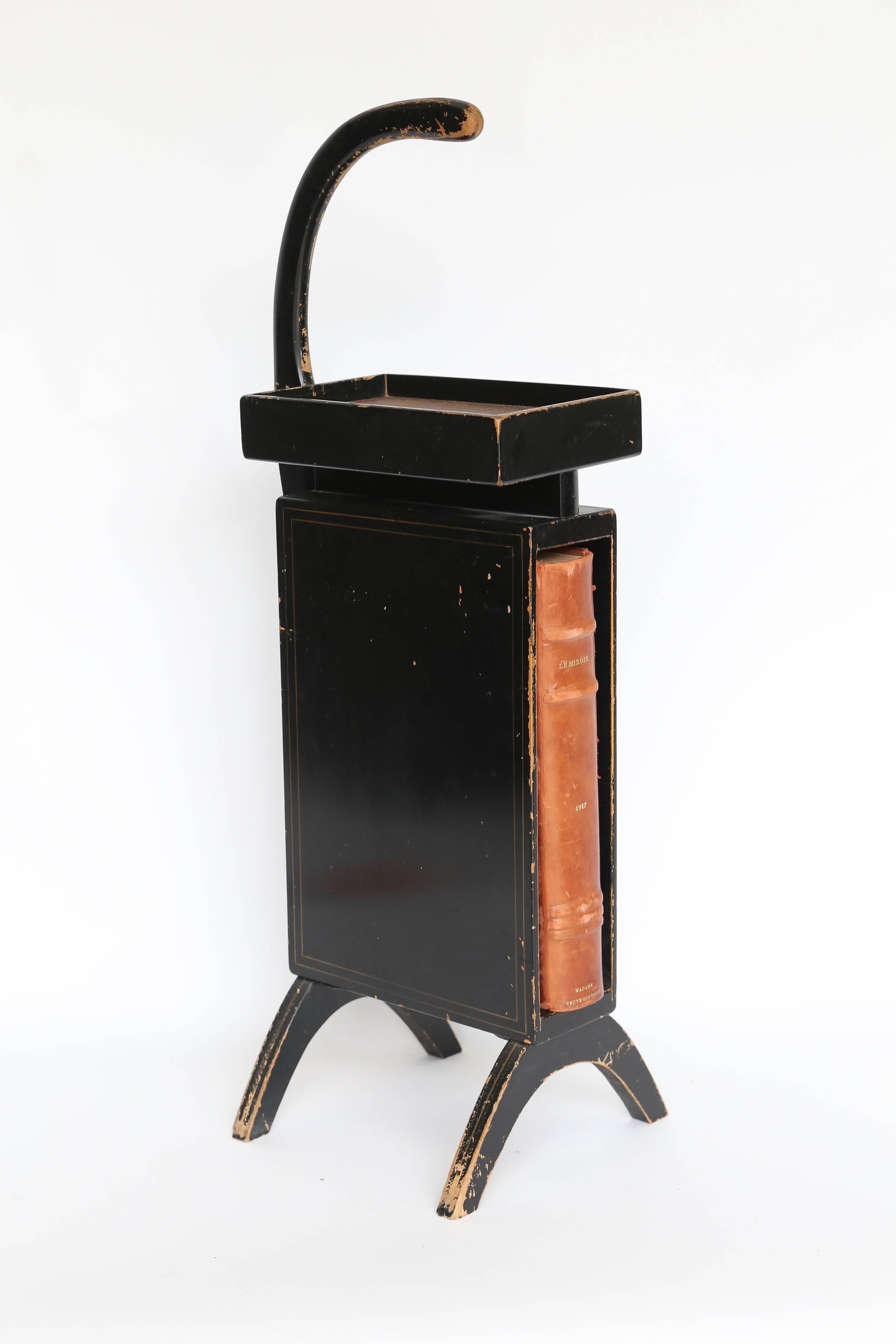 A fun and funky telephone table from back in the day! Back when telephones were attached to the wall by a cord, almost every home had a telephone table and this one is exemplary. Black wood with thin gold striping, a faux hide liner in the phone