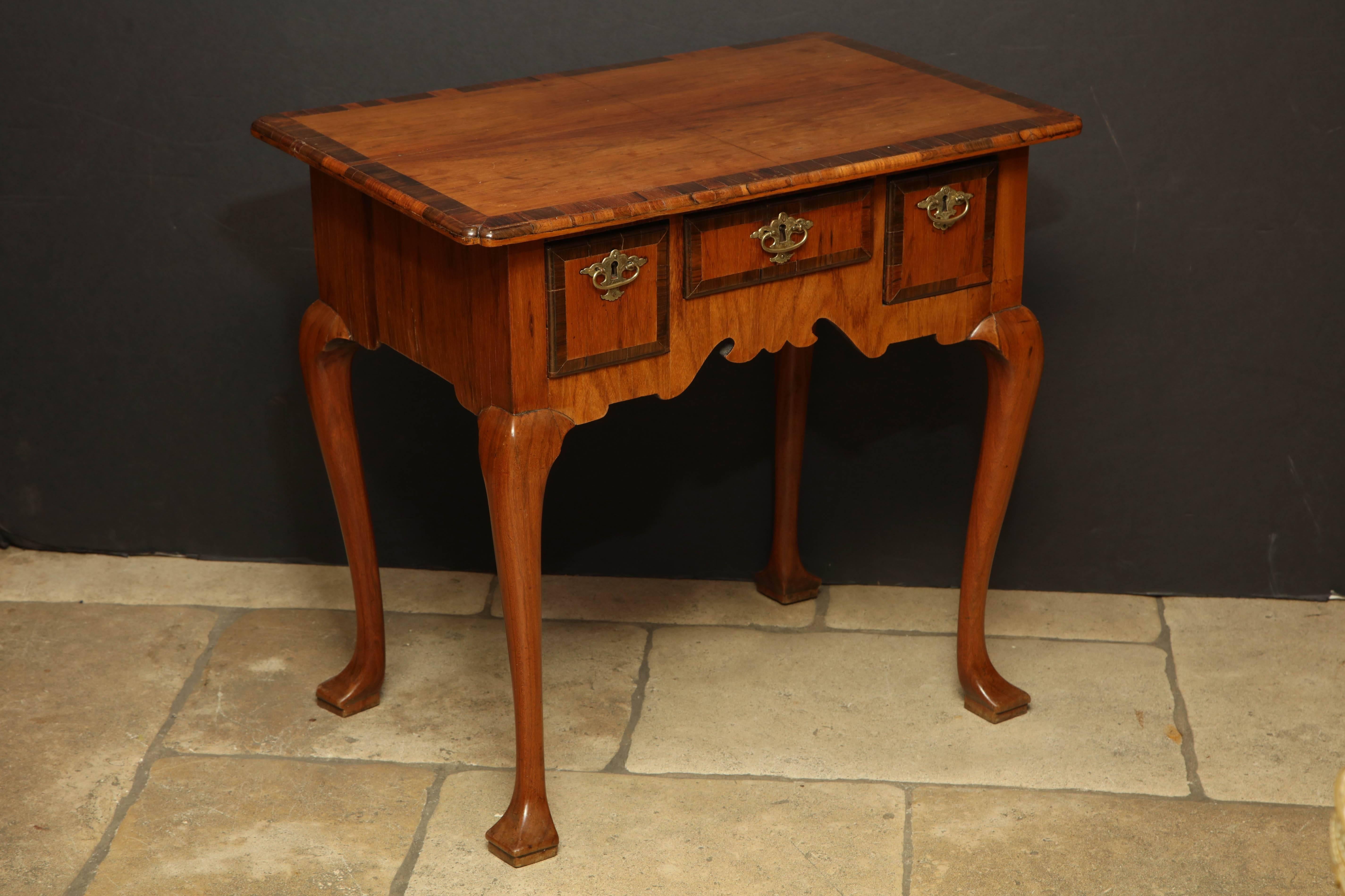 Queen Anne cross banded walnut three drawer low boy or dressing table with cabriole legs and squared trifid feet.