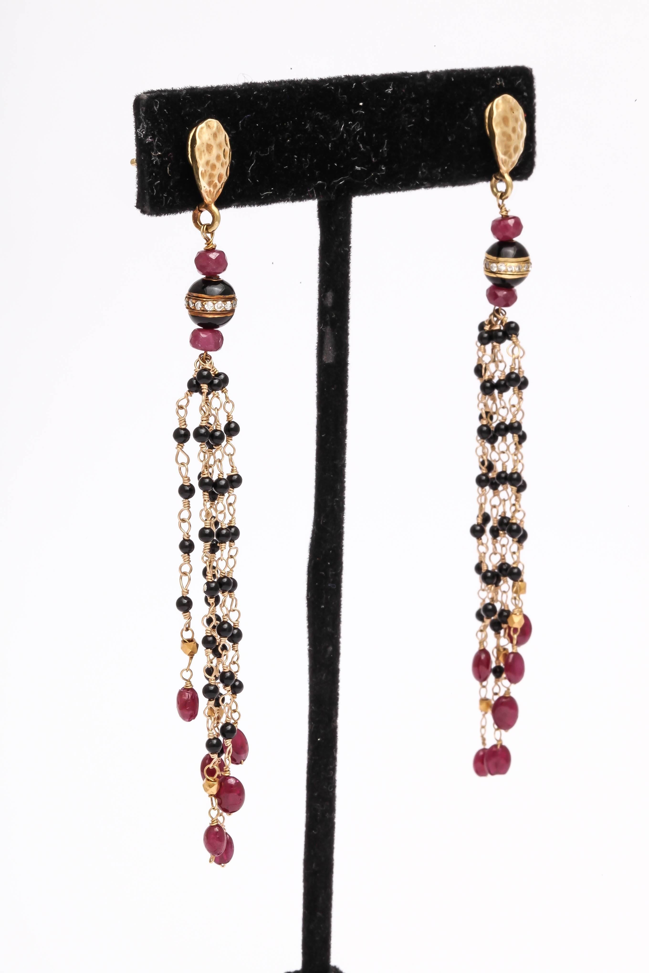 Elegantly long and graceful hand wired black onyx and ruby bead earrings. The 18 kt hammered drop shaped top holds a post, and is connected with faceted ruby beads with a diamond pave rondel sandwiched between 2 black enamel half spheres. The total