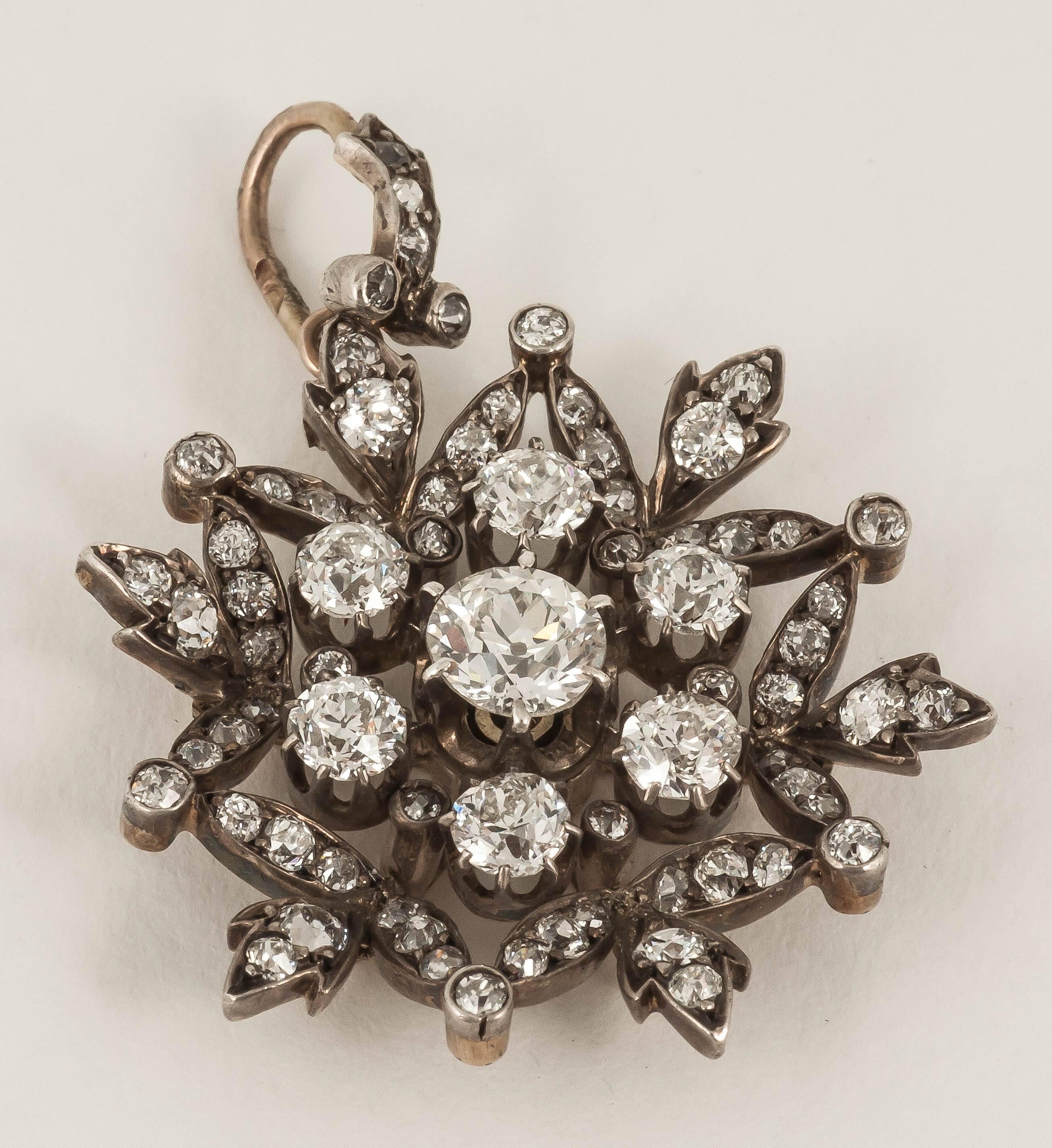 A silver and gold mounted brooch /pendant with detachable fittings,set with old brilliant cut diamonds,in the form of a snowflake.English c 1870