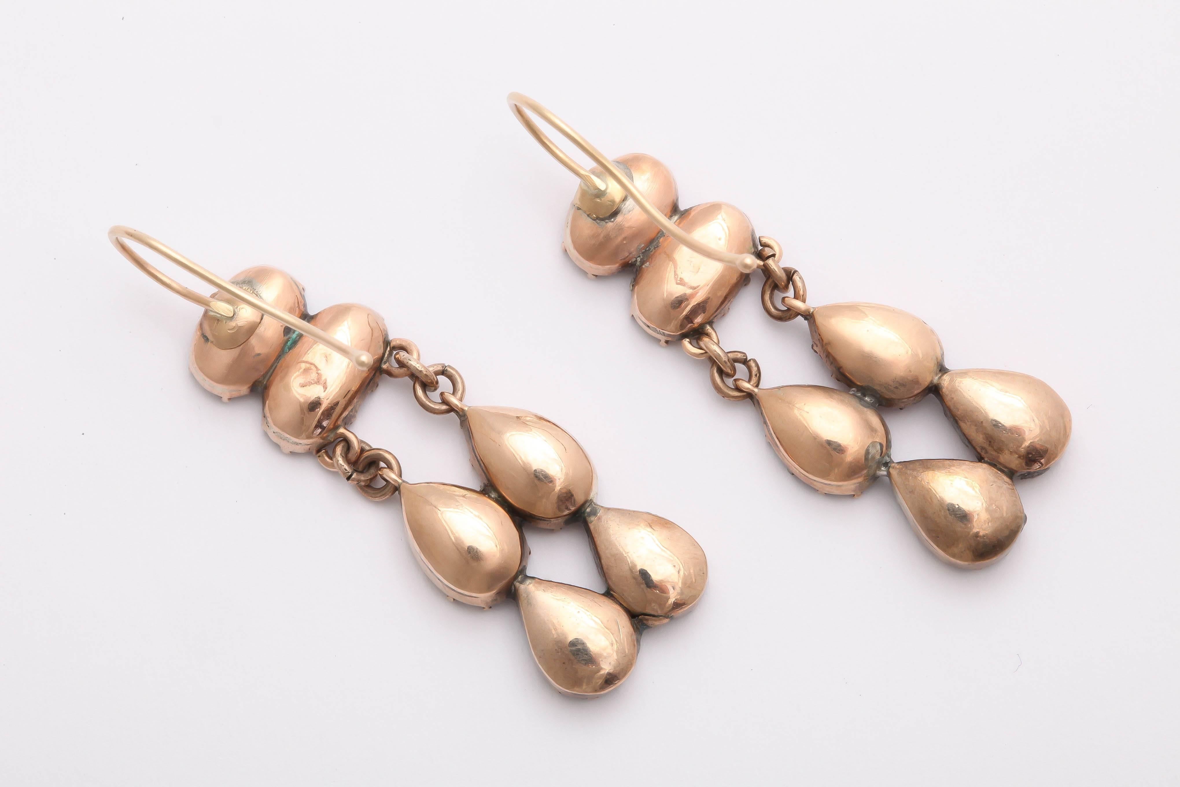 Elegant dangle drop earrings featuring almandine garnets in oval and teardrop shapes, set in 9K gold. From Georgian-era Britain.
