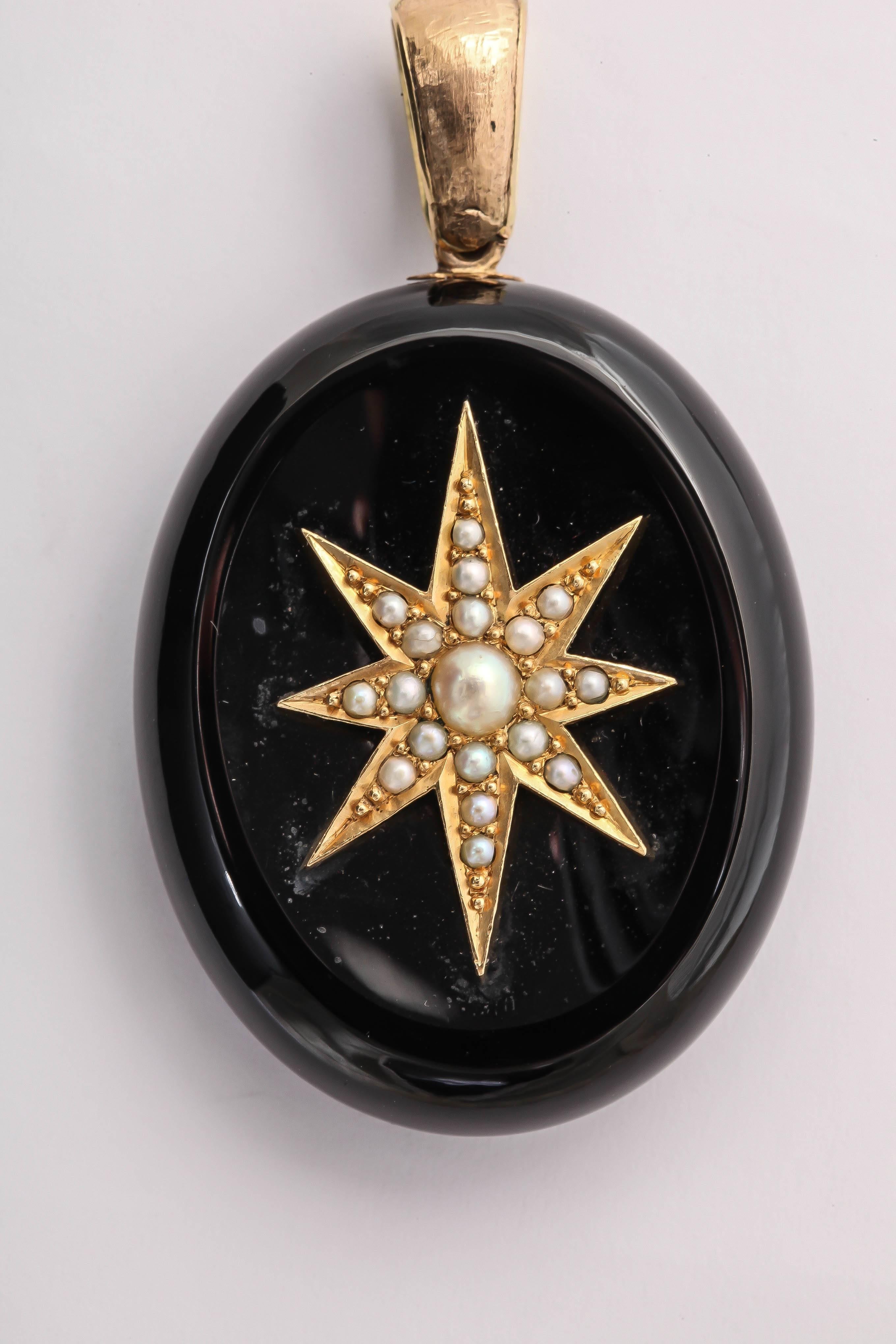 The starburst design on the front of the locket was a common design used in the Victorian era. This locket is Jet, yellow gold, and set with seed pearls. The back side has a large locket compartment. 