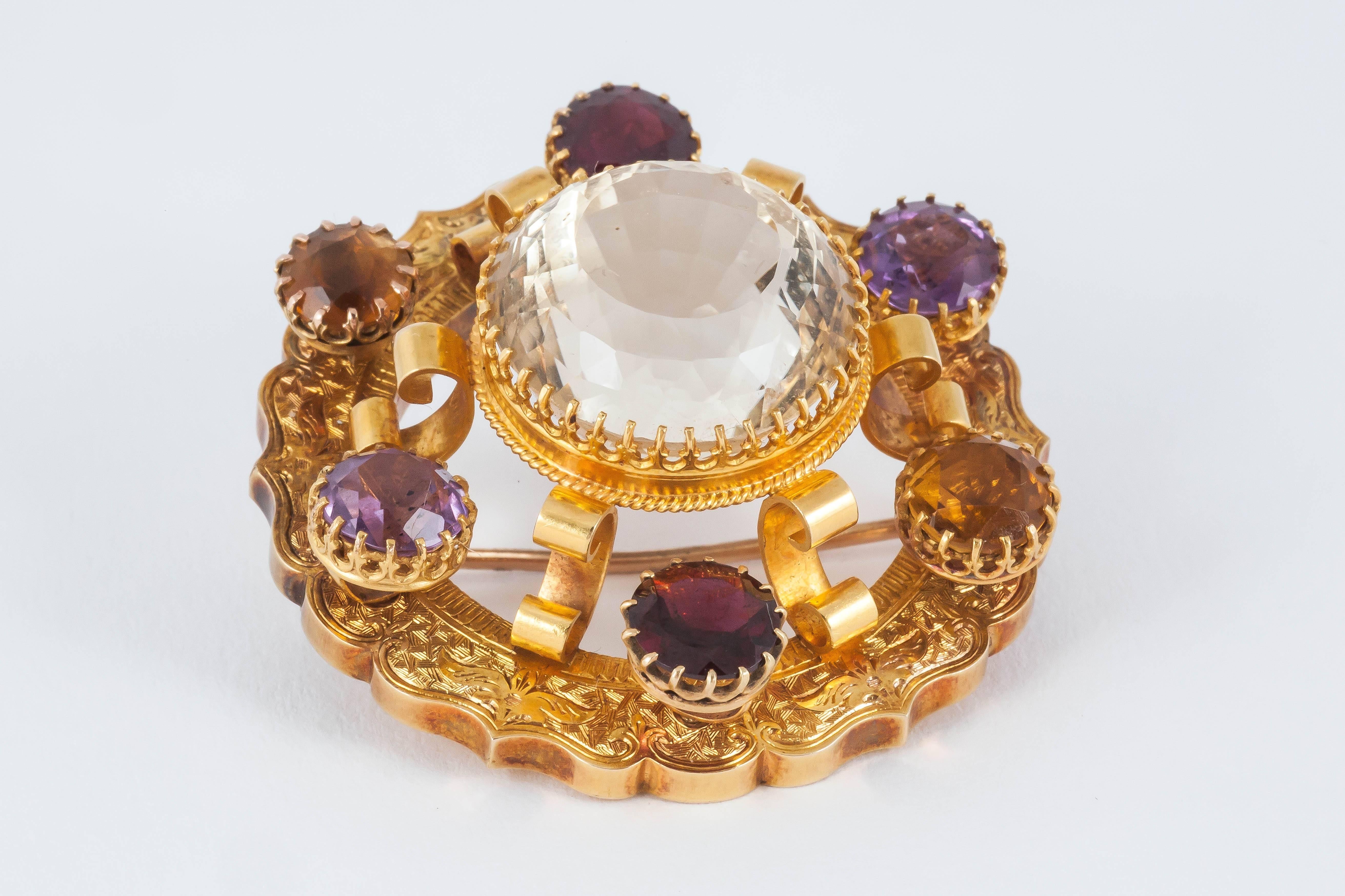A Victorian finely engraved 15 carat yellow gold antique brooch set with coloured semi precious gemstones comprising amethysts, garnets and a large central Cairngorm citrine. In excellent condition.
Measures 42mm across.
Antique piece (over 100