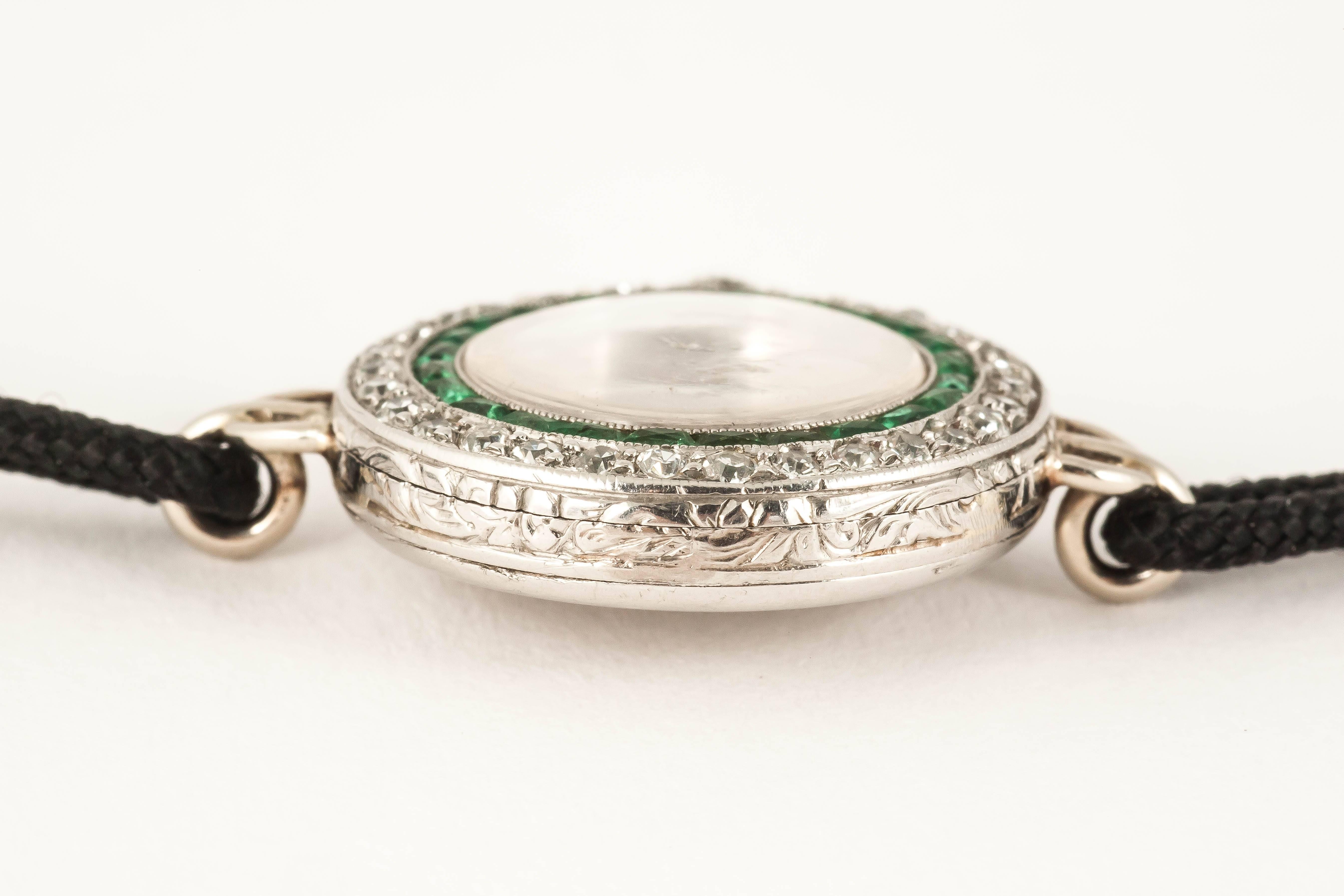 Platinum mounted ladies evening dress watch by Tiffany and Co,c,1910,set with brilliant cut Diamonds and good quality Emeralds.Platinum case RBC monogram,Haas lever 17 jewelled movement.original cord bracelrt with 14kt Gemex[USA] clasp