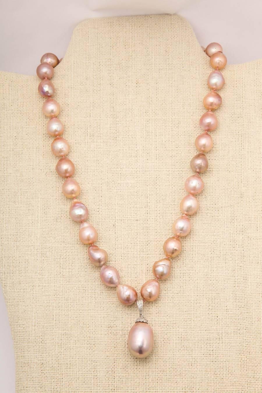 This  wonderful necklace is made of 10 x 14 mm baroque fresh water pink pearls with a 14kt white gold and diamond pearl cap and bale. The center drop pearl is 20 mm and the total pendant length is 35 mm long. The necklace is finished with a 14 kt