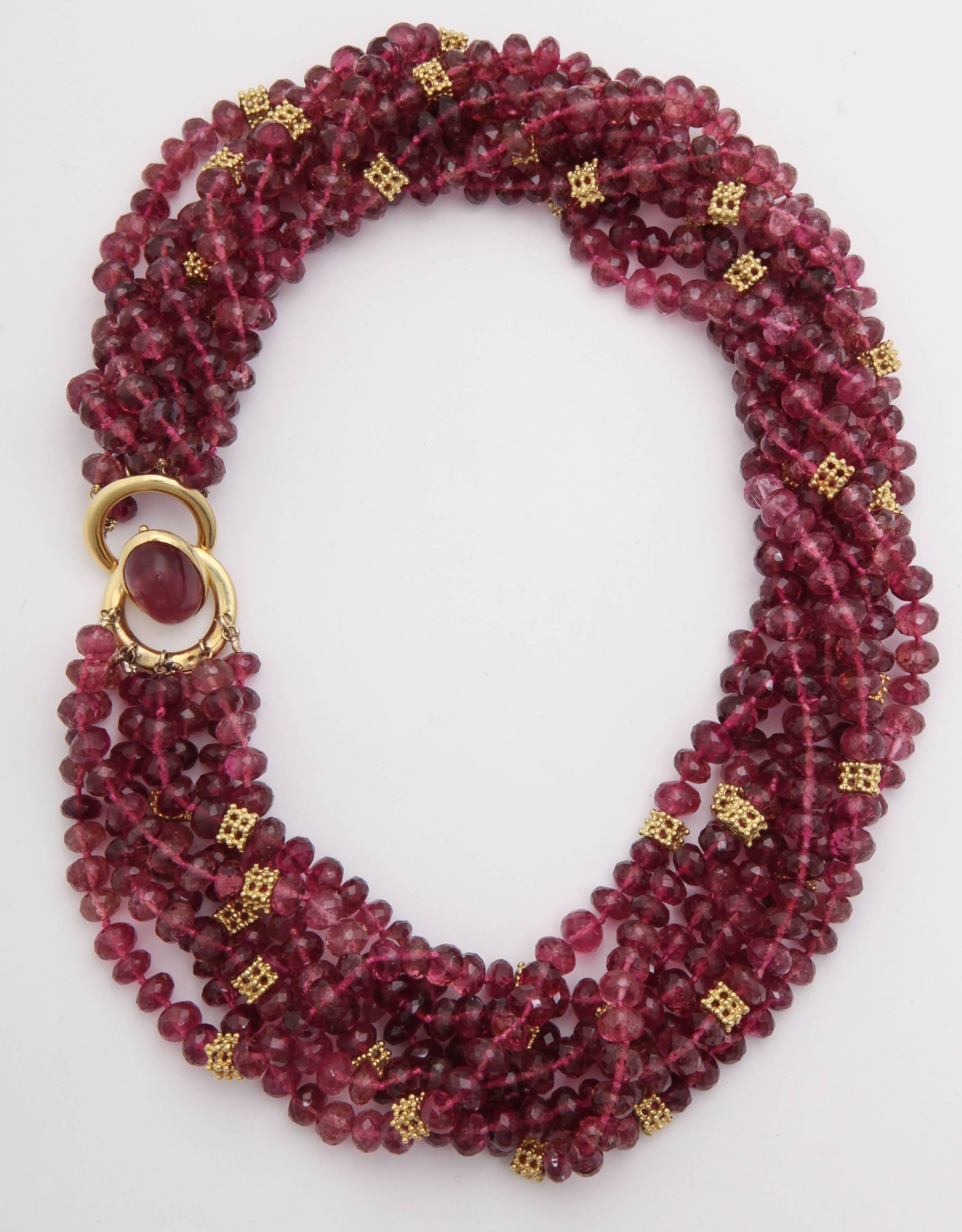 Signed Cartier Torsade necklace made up of seven strands of Faceted Pink Tourmalines with 18kt Yellow Gold pierced Spacers interspersed throughout. Signed & dated 1997 and numbered. Double Oval Gold Ring set with center Cabochon Tourmaline.  Can be