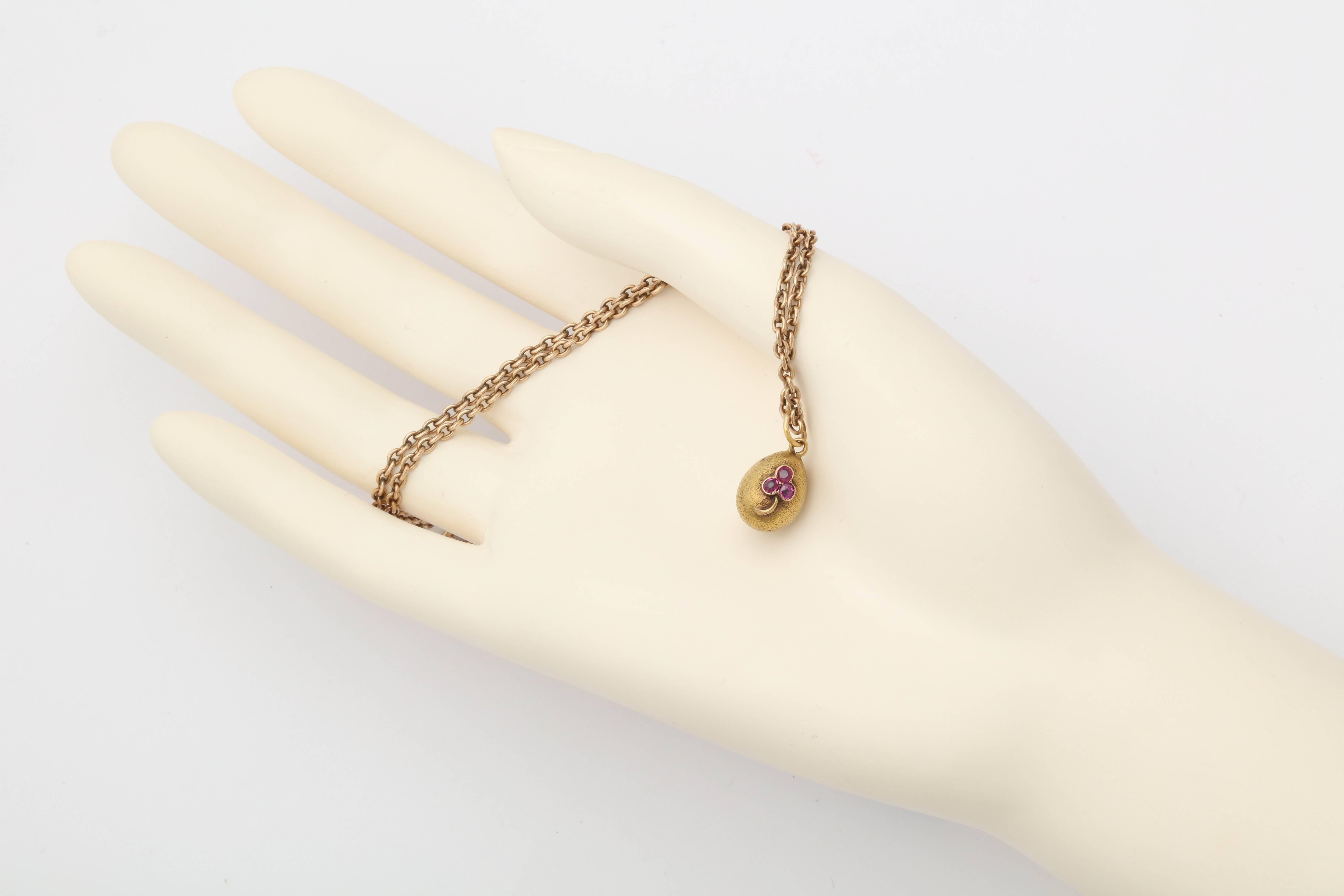 A rare Russian miniature gold egg pendant from the Romanov era, period of Nicholas II set with rubies in a 3 leaf clover motif on a textured gold base, attached to a gold suspension ring.

Stamped 56, circa 1900.

3/4 in. (1.9 cm) long including