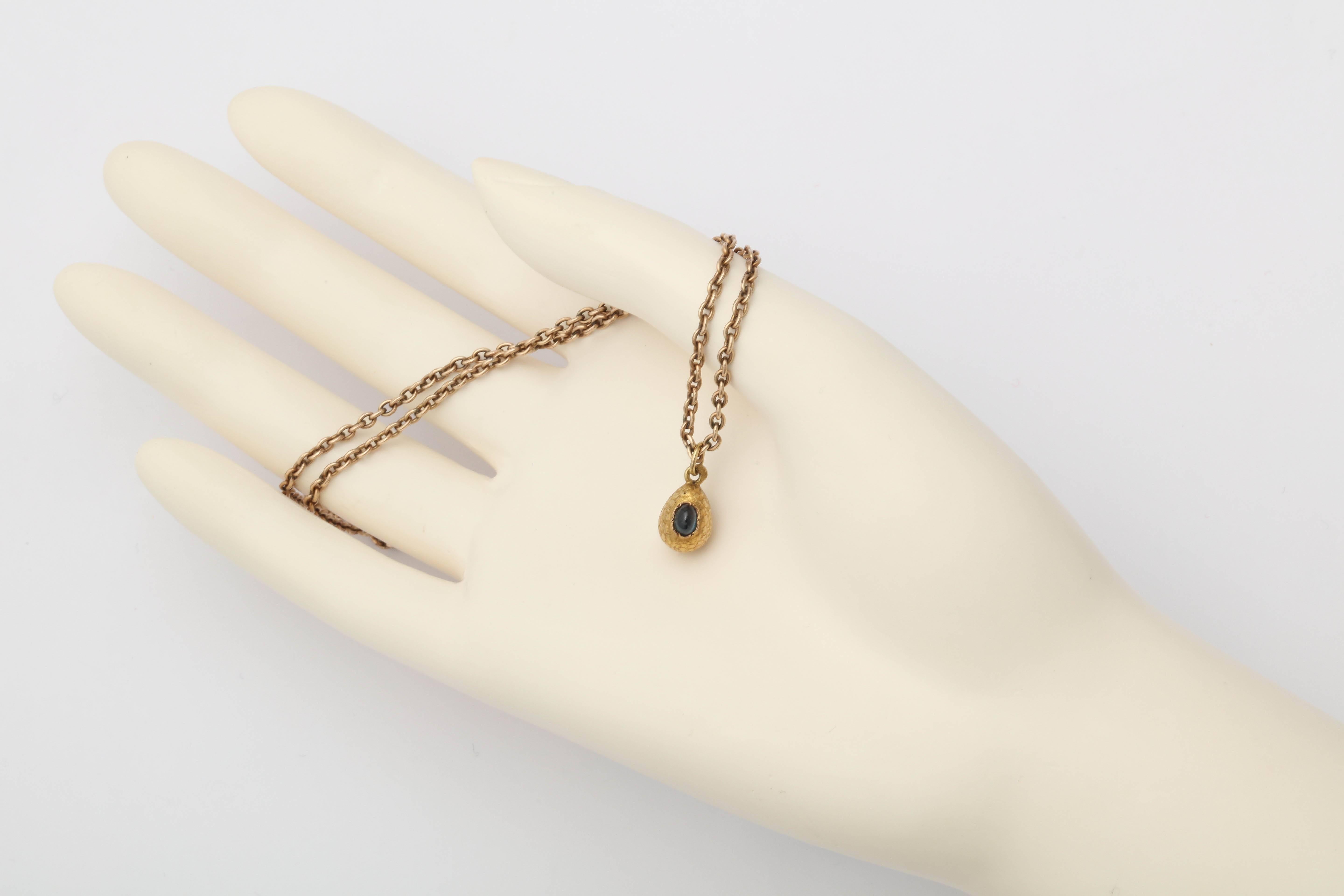 From the Romanov era, of textured gold set with a cabochon sapphire attached to a gold suspension ring.

Chain not included. 