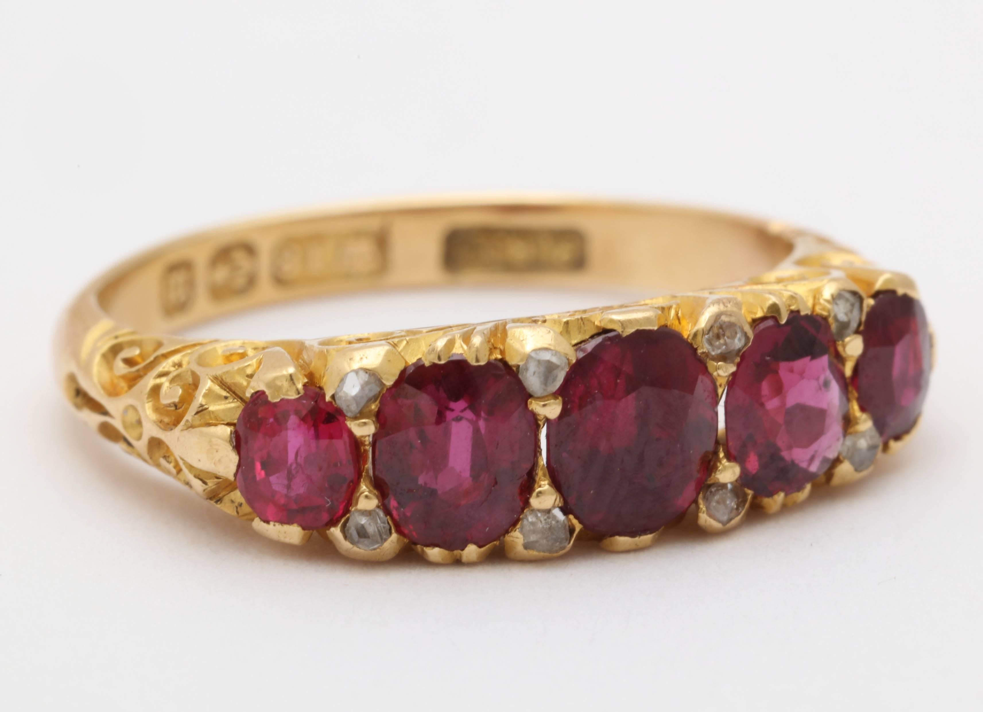 Victorian gold ring with 5 graduated faceted oval rubies and 8 small old cut diamonds, featuring scroll work on the gallery and continuing onto shoulders. 
Hallmark indicates 18K gold and an origin of Birmingham, England c.1886-1887.