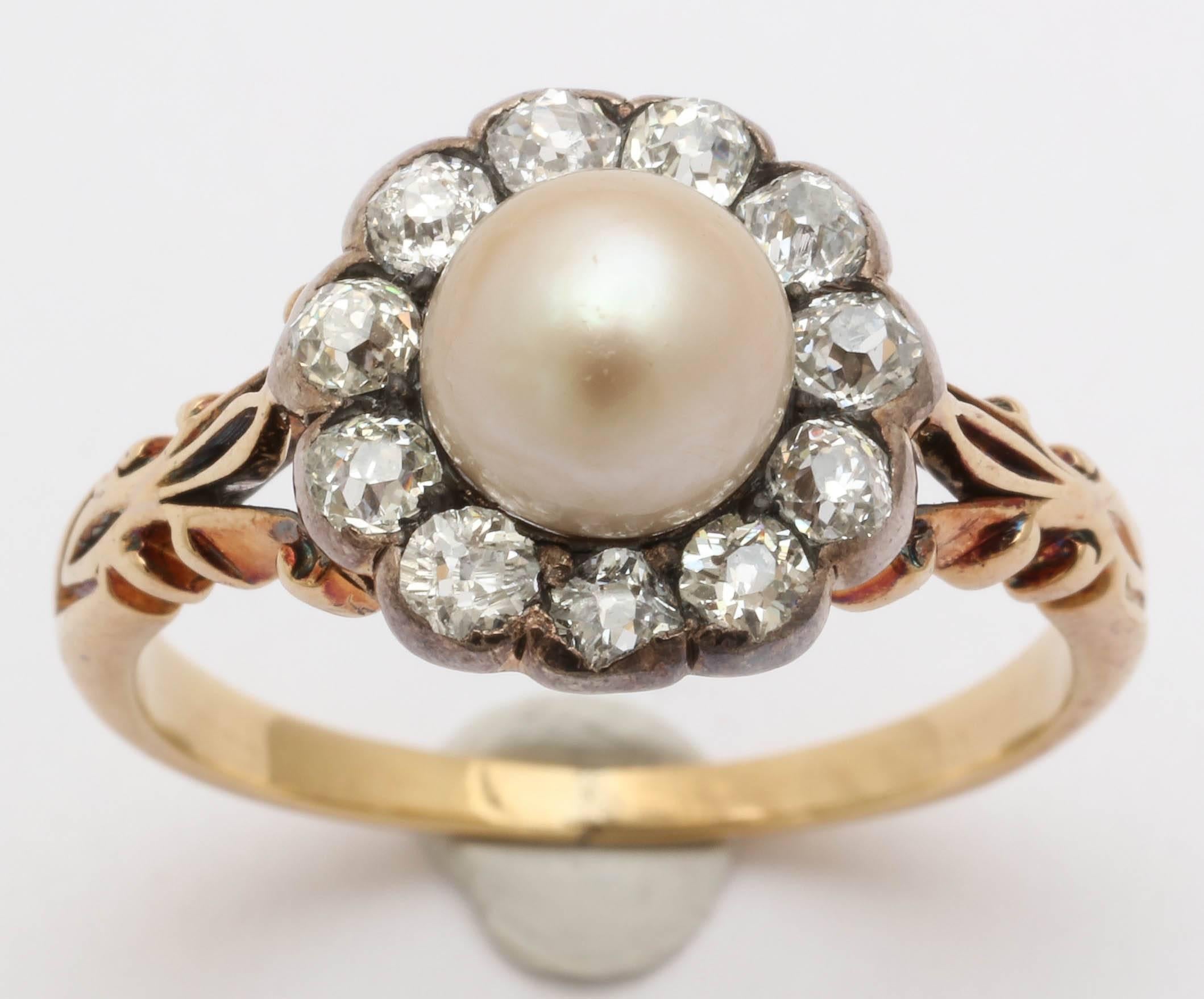 This beautiful Victorian cluster ring is set with a 6mm central pearl surrounded by 11 old mine cut diamonds approximately .5-.7 carats each. The diamonds and pearl are set in silver. Ring is 15kt. Lovely openwork on each shoulder. 