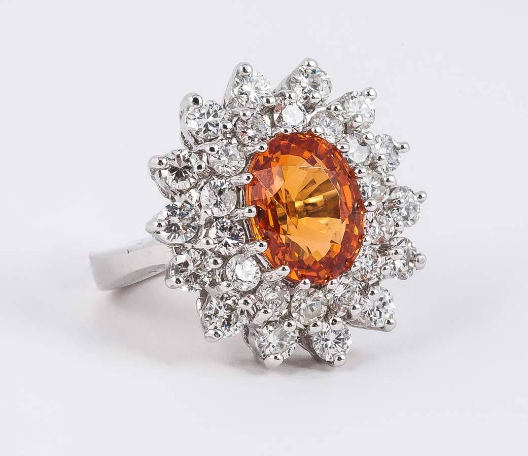 1960's cluster ring. Center stone of Spessartite Garnet surrounded by approx. 2 cts of diamonds in 18ct White Gold
