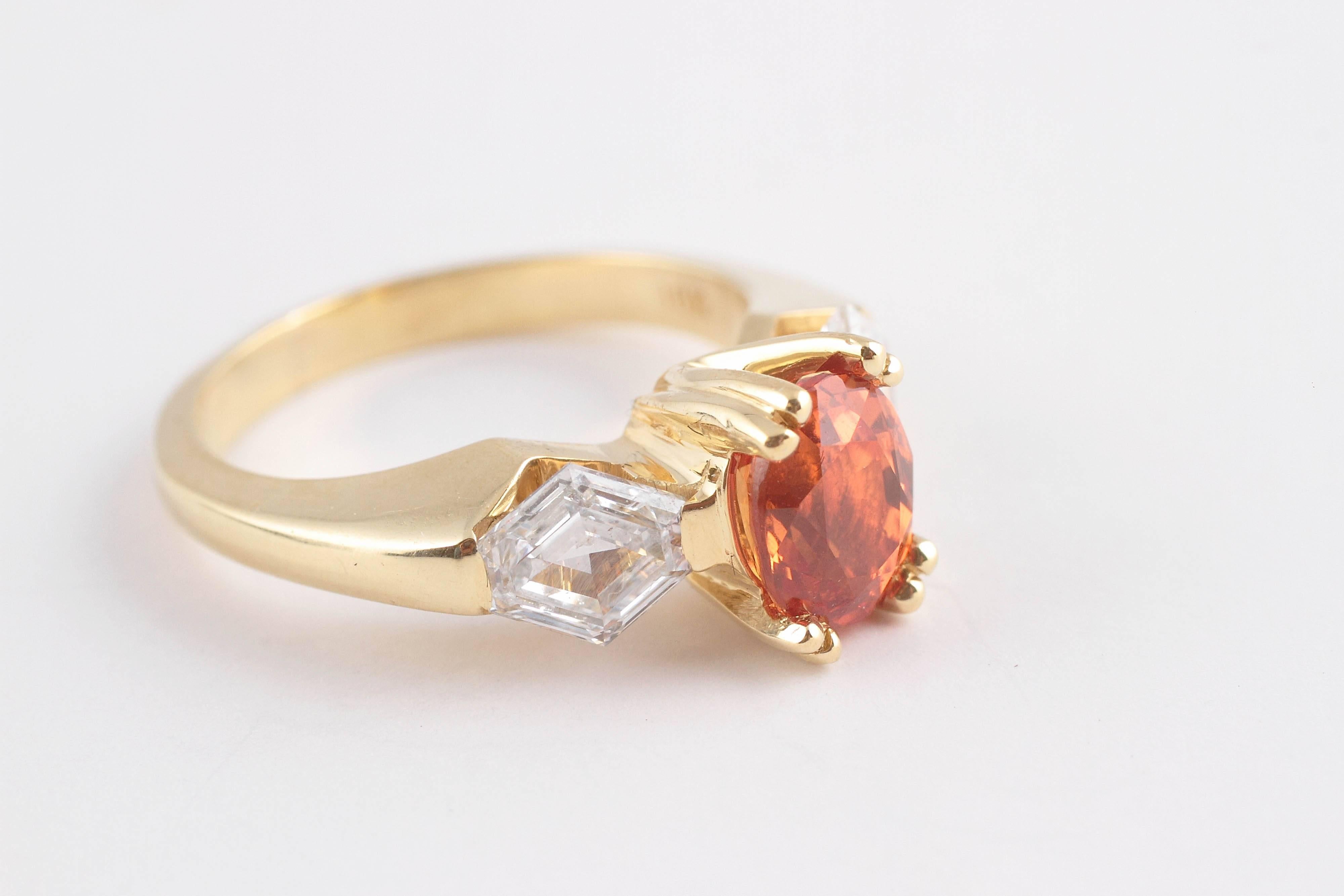 In 18 karat yellow gold, centered with an oval-shaped orange sapphire, 1.78 carats and flanked by 2 lozenge-shaped diamonds with a total weight of 1.15 carats. Size 6.