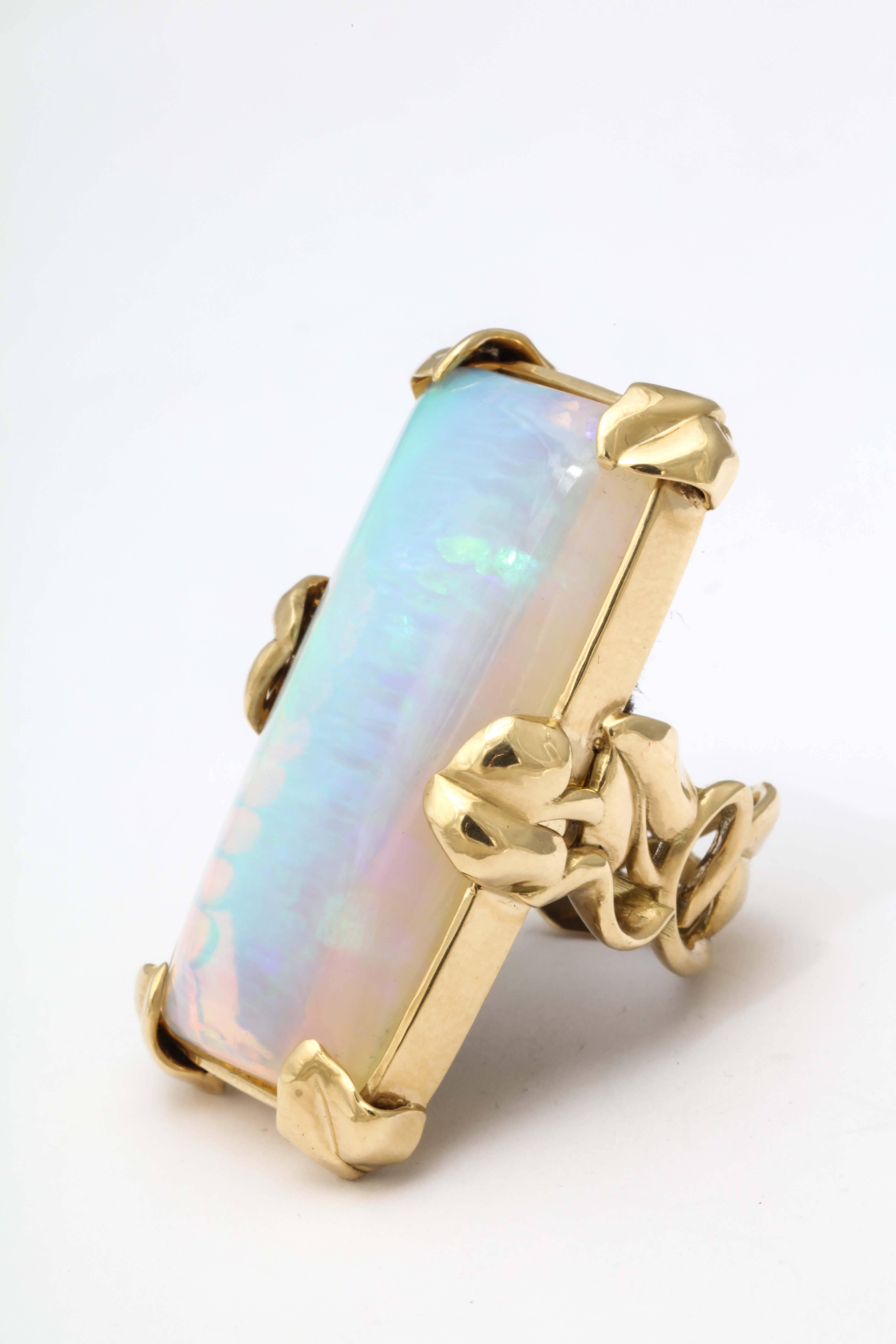 An 18kt yellow gold and opal ring. The cushion cut opal is set into an 18kt yellow gold frame with 6 lily pad prongs holding the stone in place. The shank is composed of woven lily pads and lilies, size 7.5. The opal weighs 50.46cts.
length: 1.75