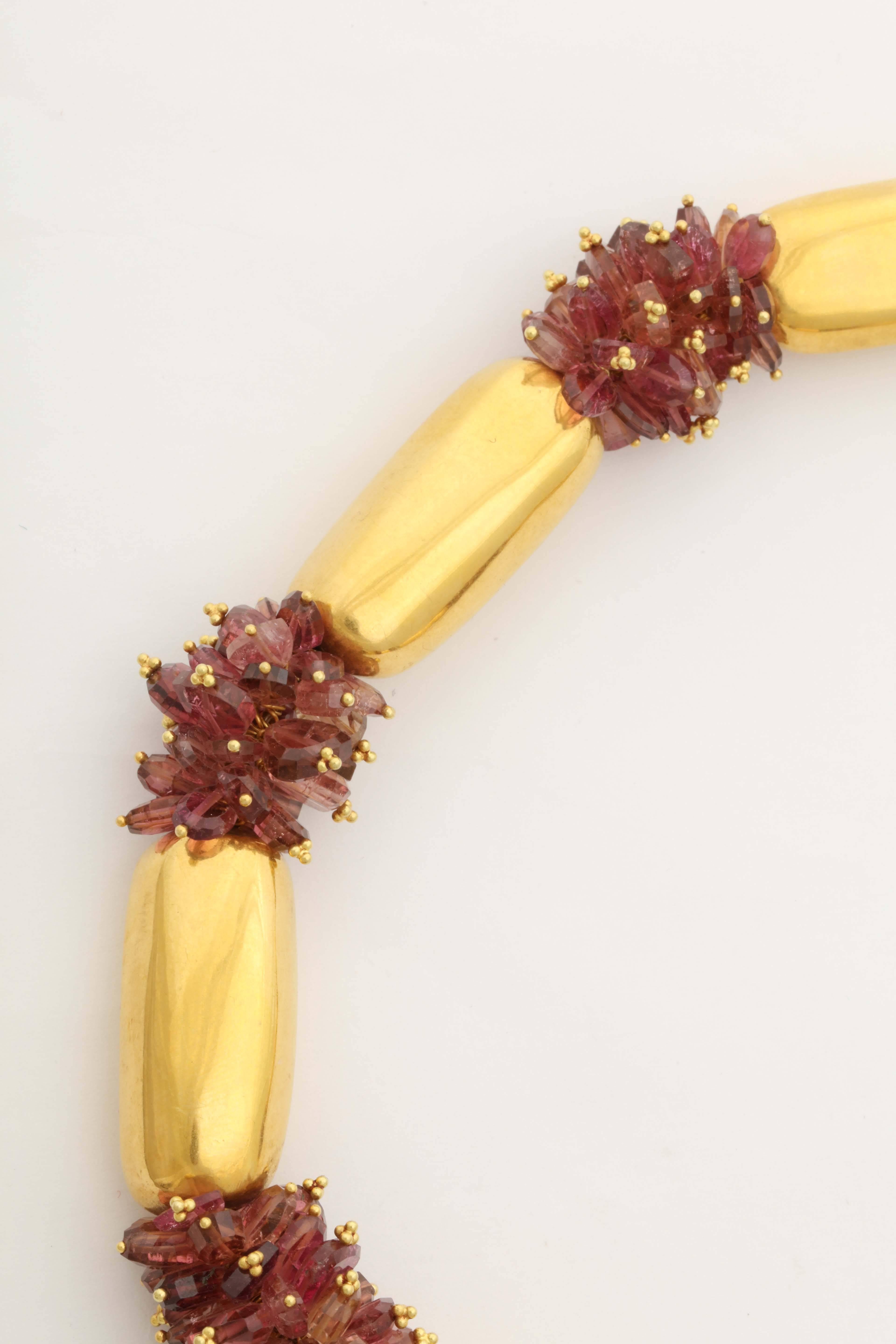 A necklace composed of 18kt yellow gold beads and clusters of pink sapphire and tourmaline beads. Each sapphire and tourmaline bead has been turned into a drop using an 18kt yellow gold bud headpin. The drops are then stacked to form clusters, which