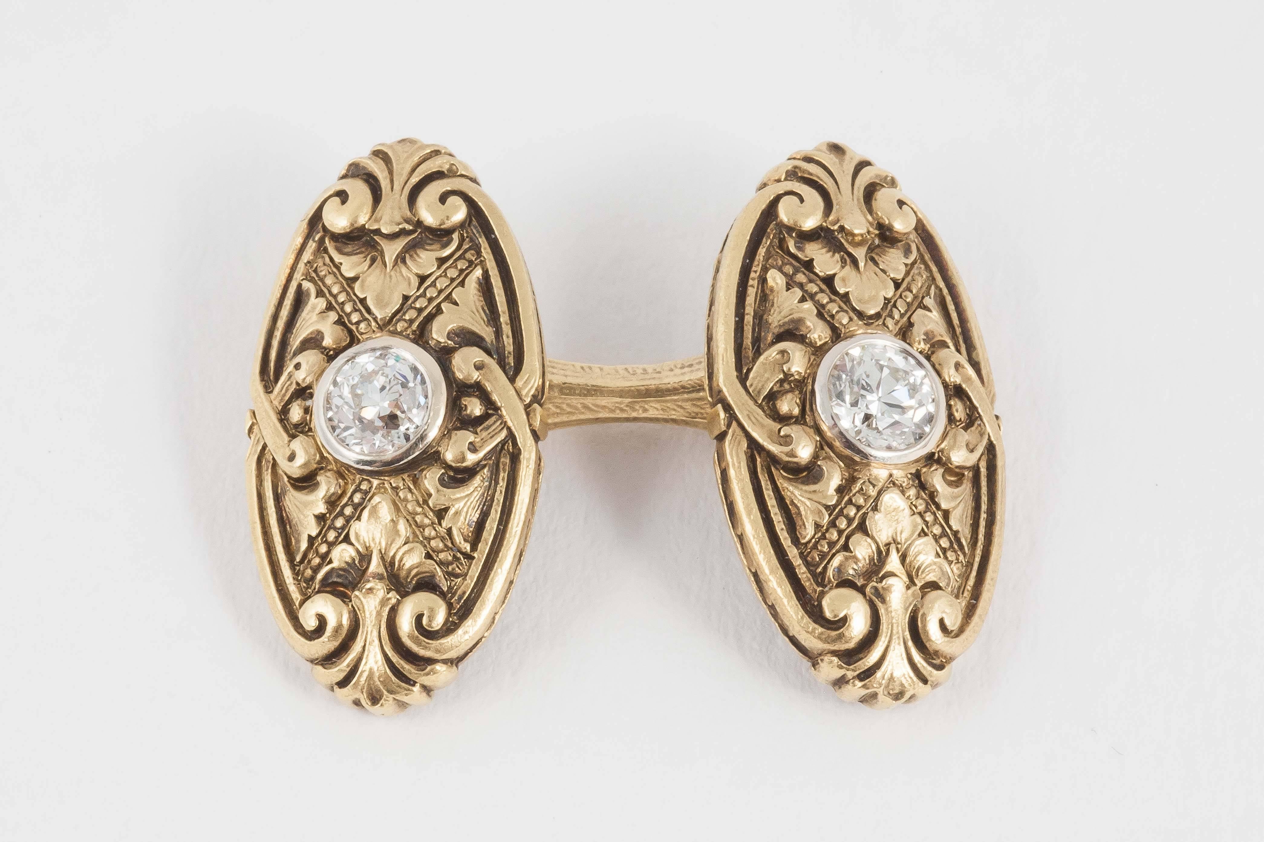 A heavy pair of double sided antique cufflinks with deeply carved scrolls on both front and reverse faces, in 14 karat yellow gold, set with an old cut diamond centre. Oval in shape.
Measures 18mm in height x 10mm in width.
Antique piece (over 100