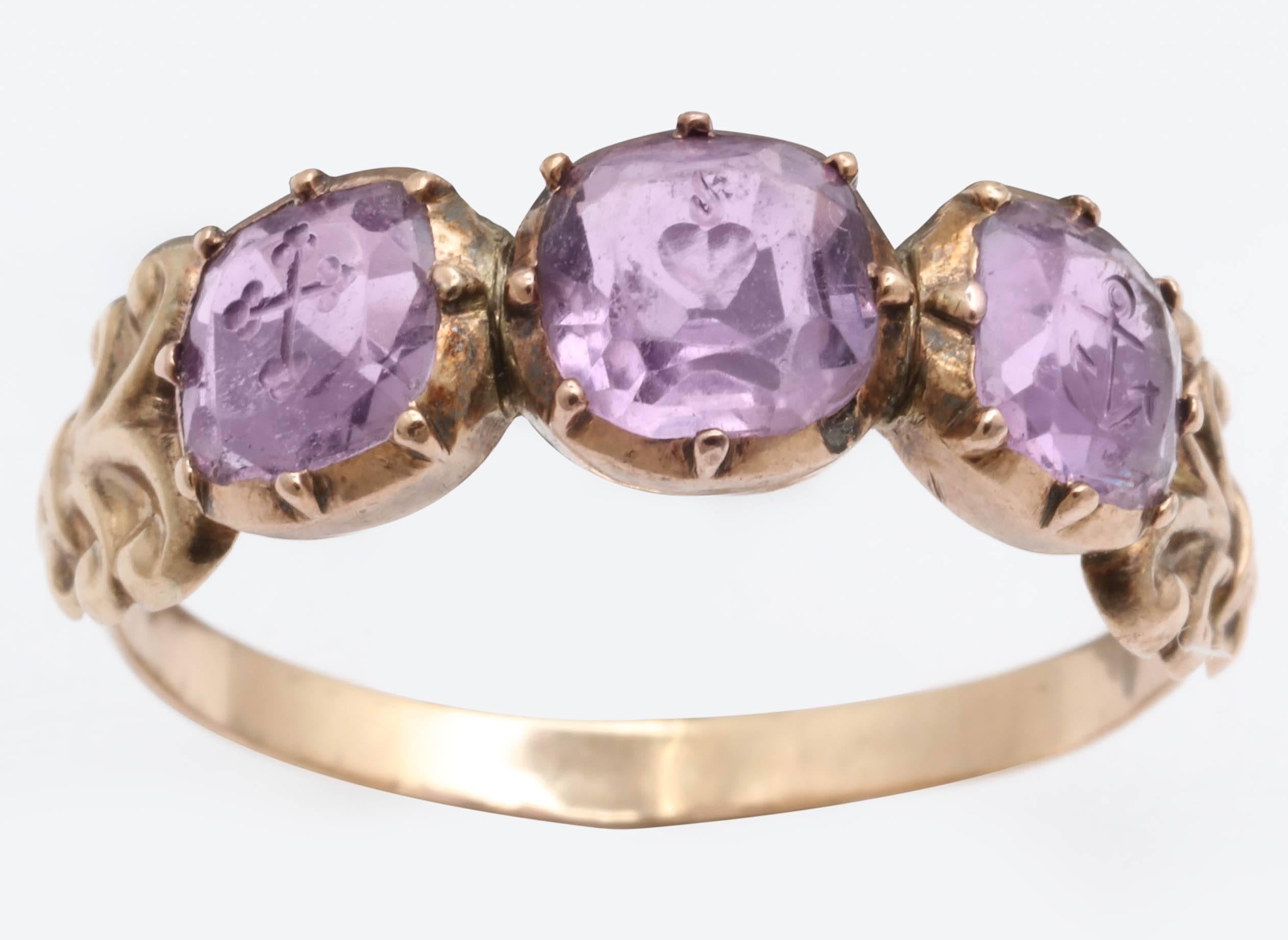 Dieser göttliche und sehr seltene frühviktorianische Ring mit drei Steinen ist mit drei Amethysten besetzt. Jeder Amethyst ist von links nach rechts mit einem Kreuz, einem Herz und einem Anker graviert. Diese drei Symbole, die für Glaube, Hoffnung