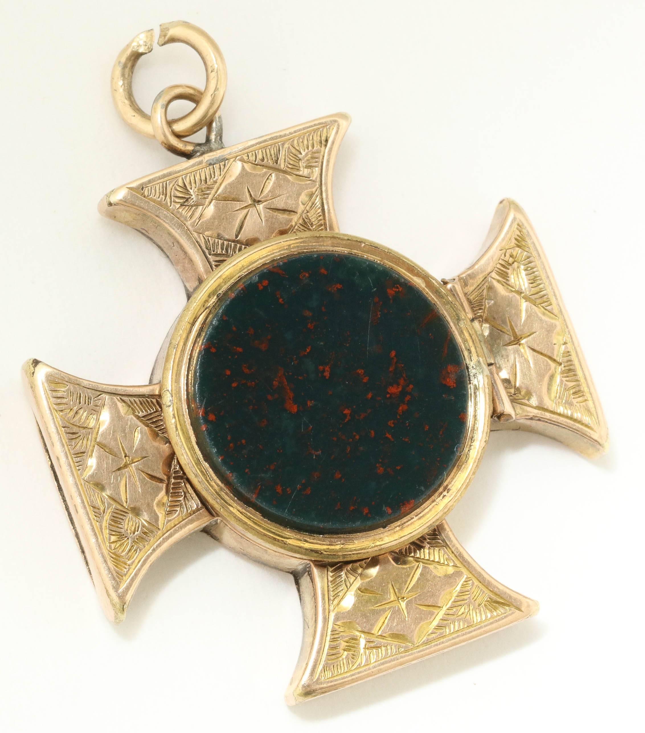 Beautifully engraved on the front and back, this maltese cross pendant is set on the front with a bloodstone and on the back can be opened to reveal a locket compartment. It is English and made in 9K yellow gold. Maltese crosses are steeped in