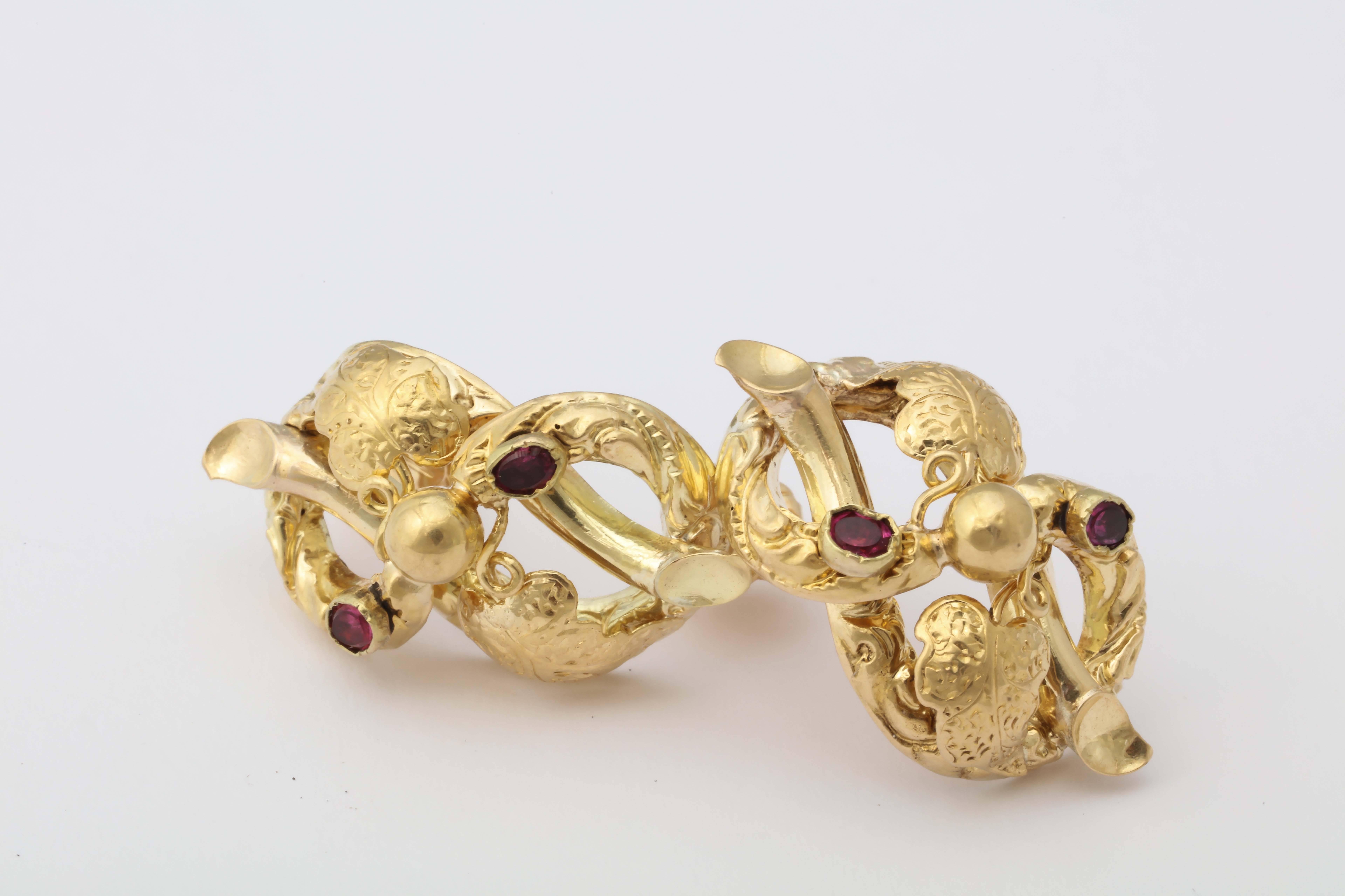 Designed as curved gold grape leaves enhanced with red garnets. Fitted with gold posts for pierced ears. 
Circa 1890

Each cluster measures approx-1 1/8 in. (2.9 cm.) long.
