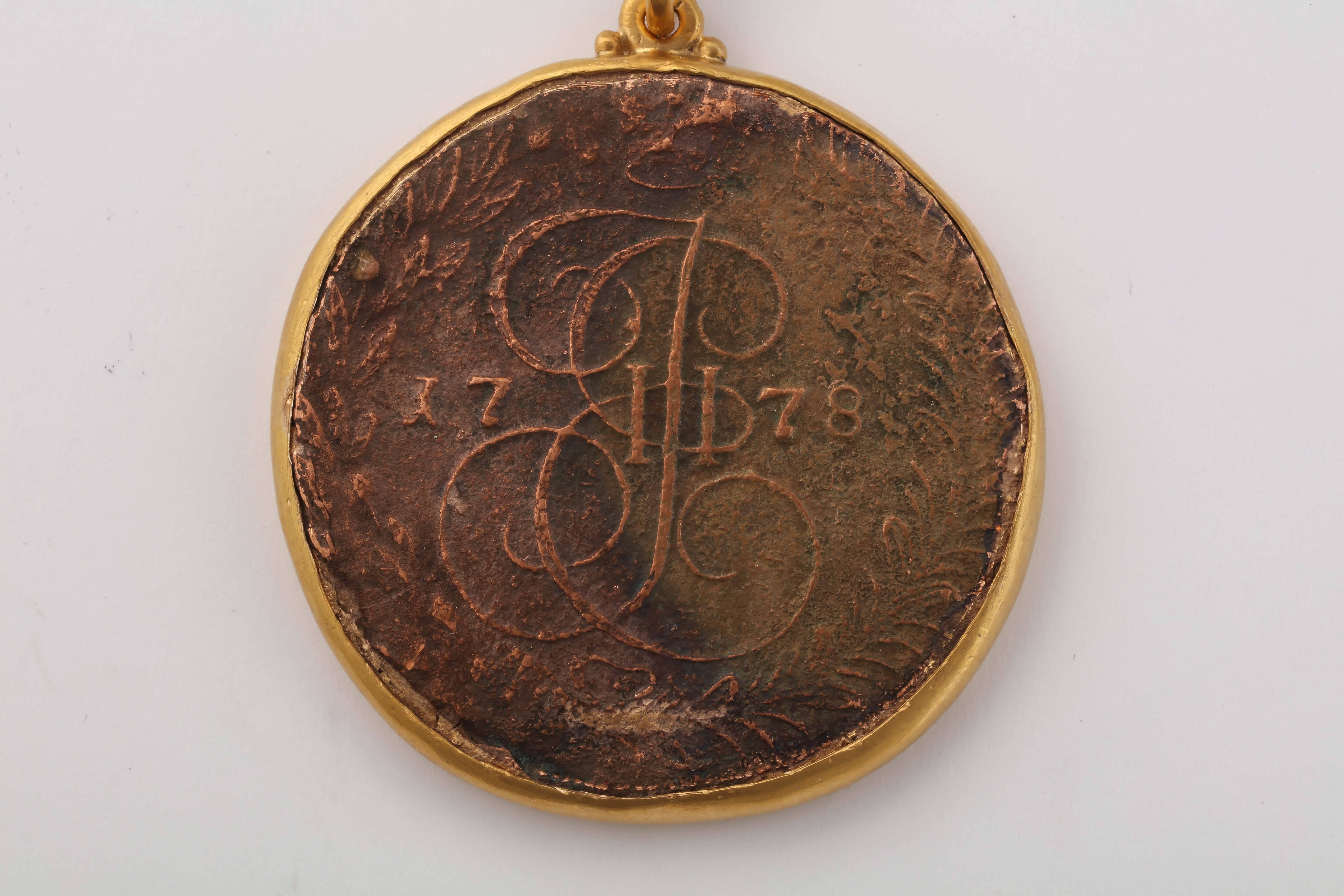 An original copper coin from the era of Empress Catherine the Great (r. 1762-96) mounted as a pendant, with the date of 1778 on the front and the Empresses' cypher, the Romanov double headed eagle on the reverse. Fine copper tone. Chain not