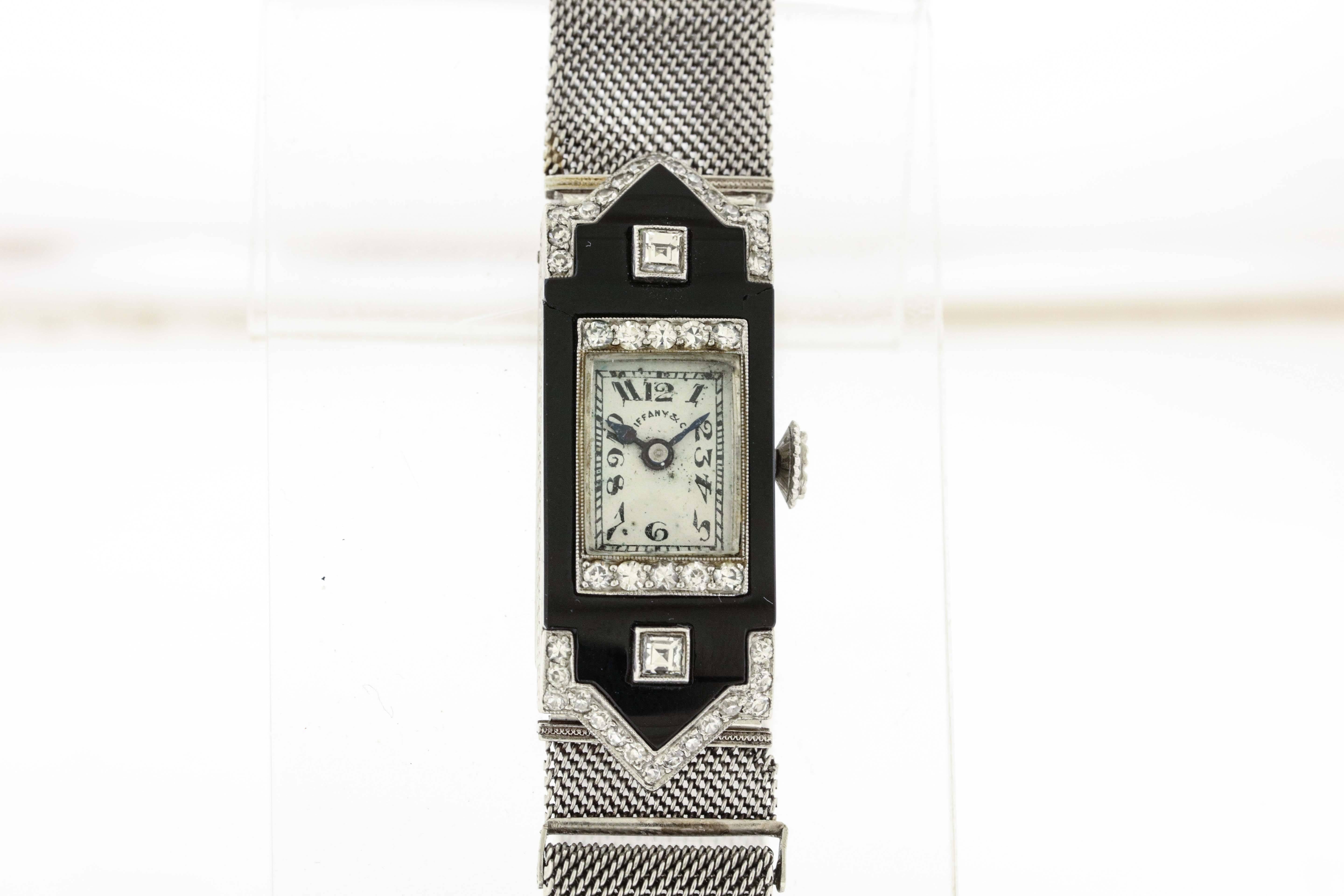Platinum Patek Philippe & Cie, Genève, for Tiffany & Co, circa 1924, is a fine Art Déco, platinum,  diamonds and onyx rectangular,women's wristwatch with platinum and diamond mesh band. The 13mm x 30mm platinum hinged case, is decoratively