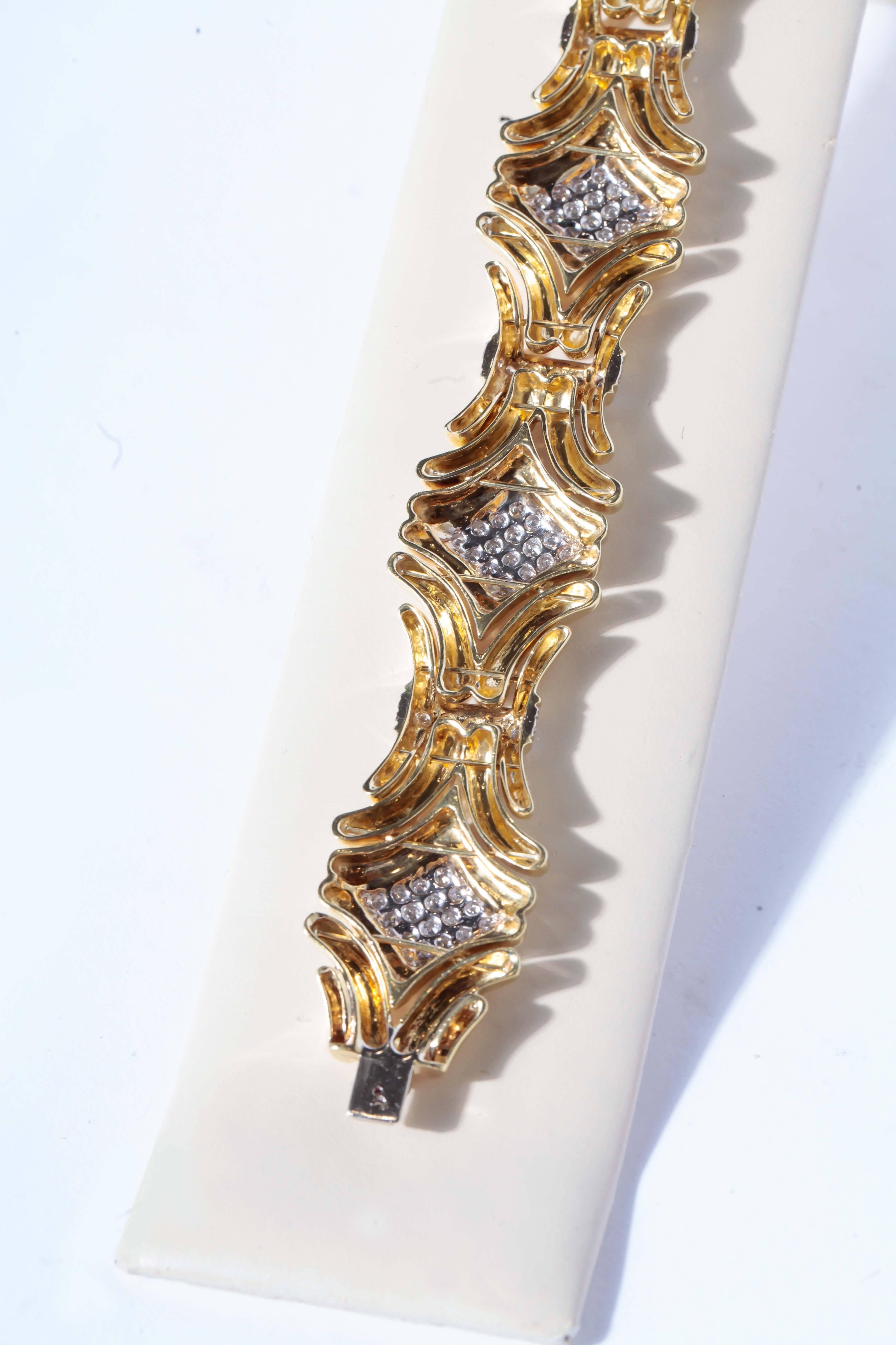 This is a spectacular 18 karat yellow gold and diamond link bracelet measuring 7 inches in length and 1 inch width. The round brilliant cut diamonds are pave set in diamond shapes with gold accents, and the links are connected with four diamond