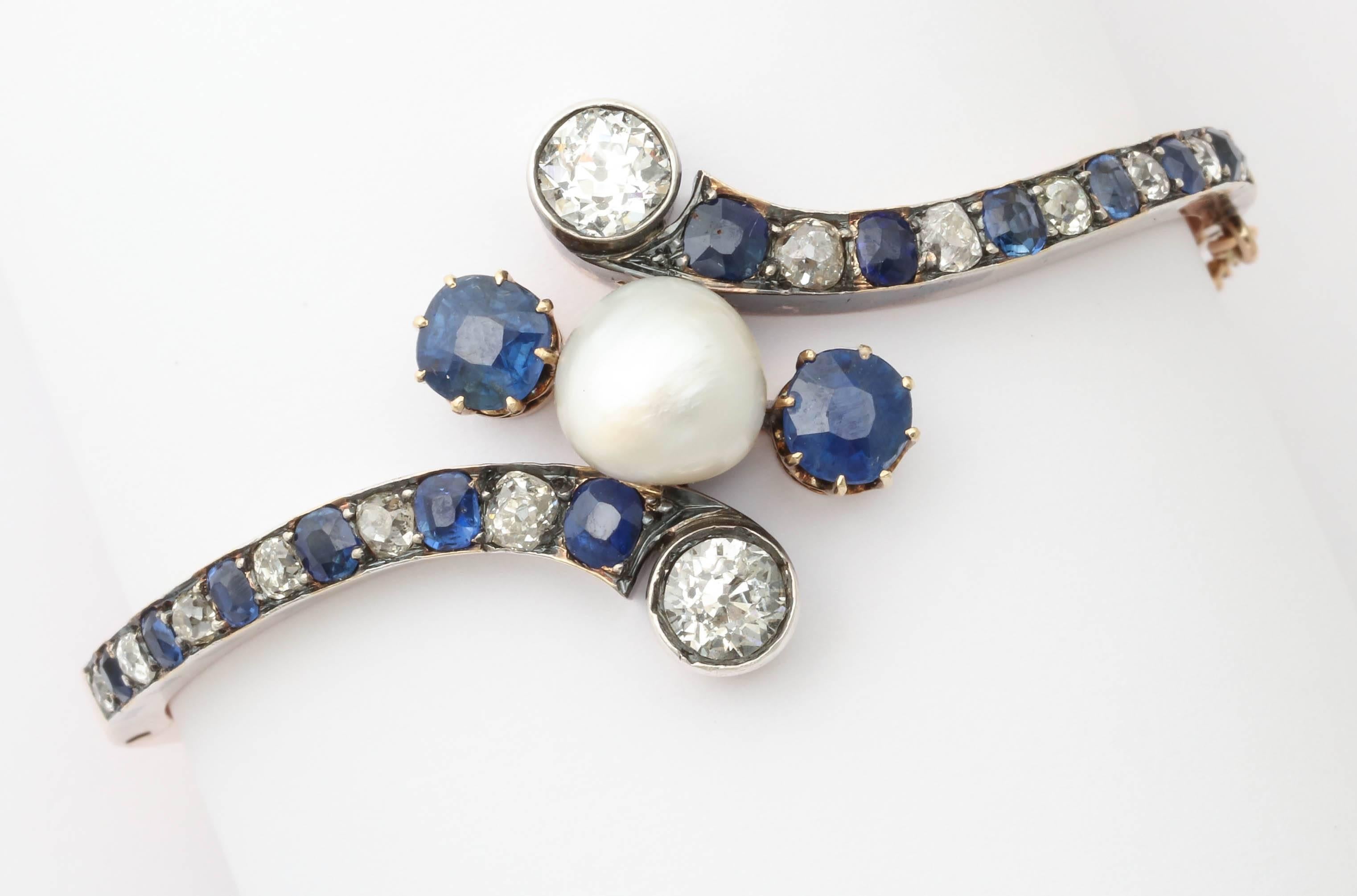 A fabulous bracelet in its original box. A large natural pearl (approx. 9mm) is set in the center with two Old European cut diamonds weighing approximately 1.2ctw and two sapphires weighing approximately 2.1ctw set around it. Set into the bracelet