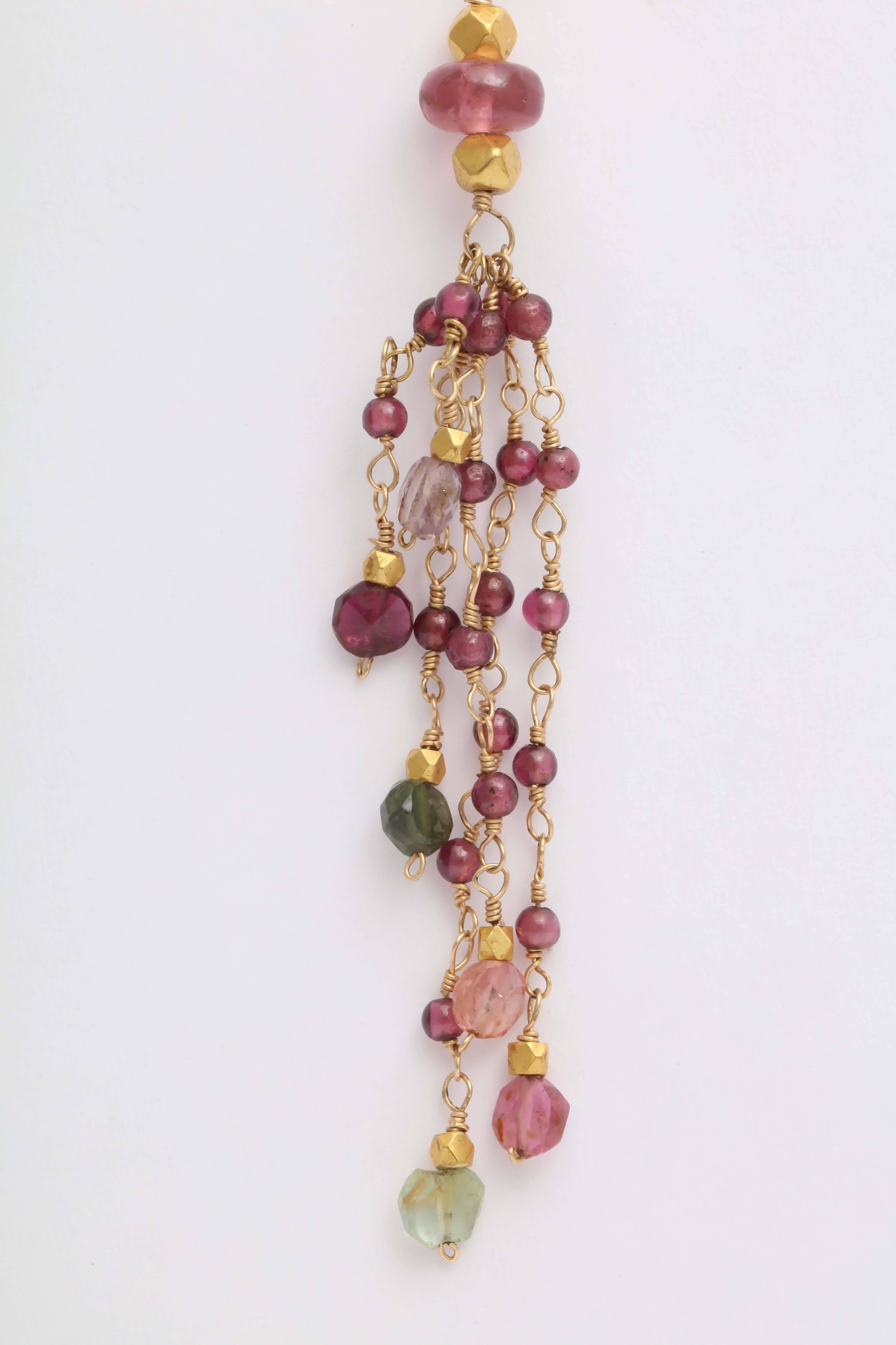 Delicate 2 mm round garnet beads, gold beads and faceted tourmaline bead are wired together in a long graceful dancing earrings. The top of the earrings are  beautifully carved with a flower design in gold and holds the ear wire securely. The total